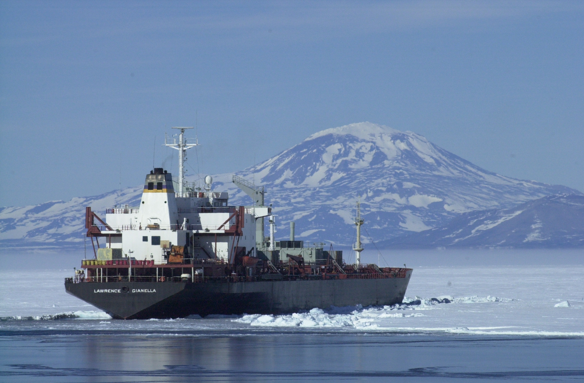 Ship in ice with mountain behind.