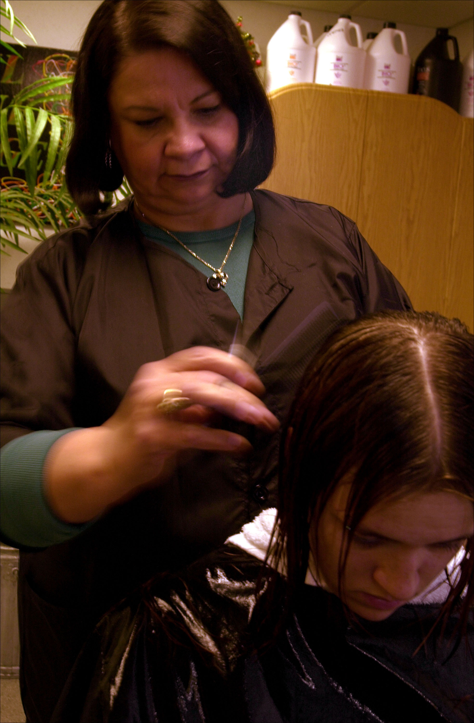 A woman cuts another woman's hair.