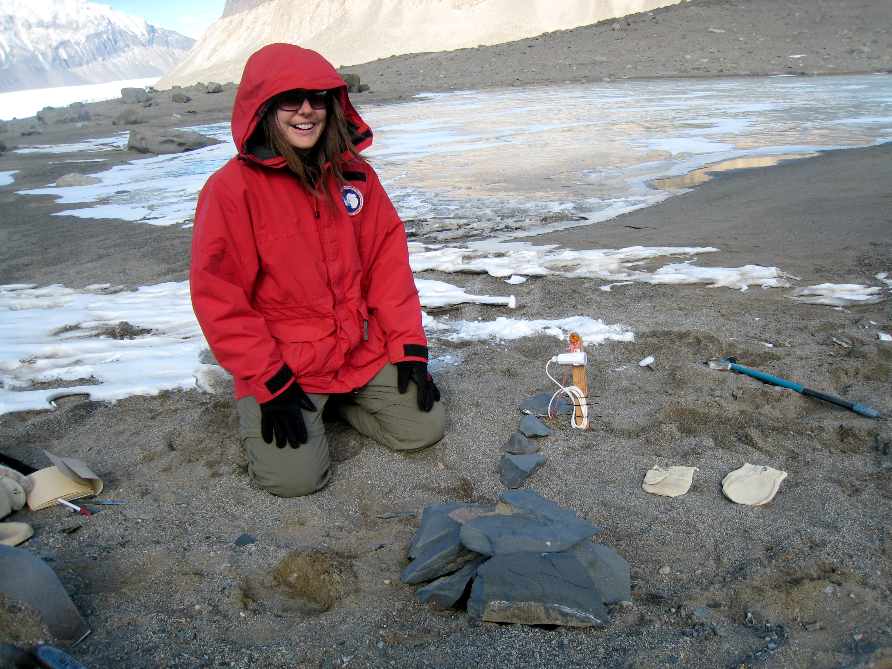 Person kneels on rocky landscape.