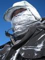A man with a snow-encrusted scarf across his face.