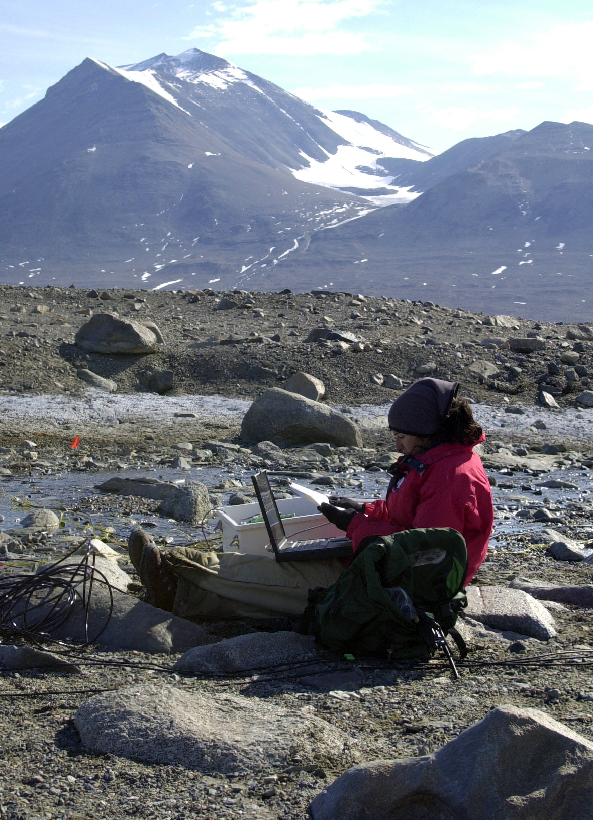 A woman with laptop computer in rocky area.