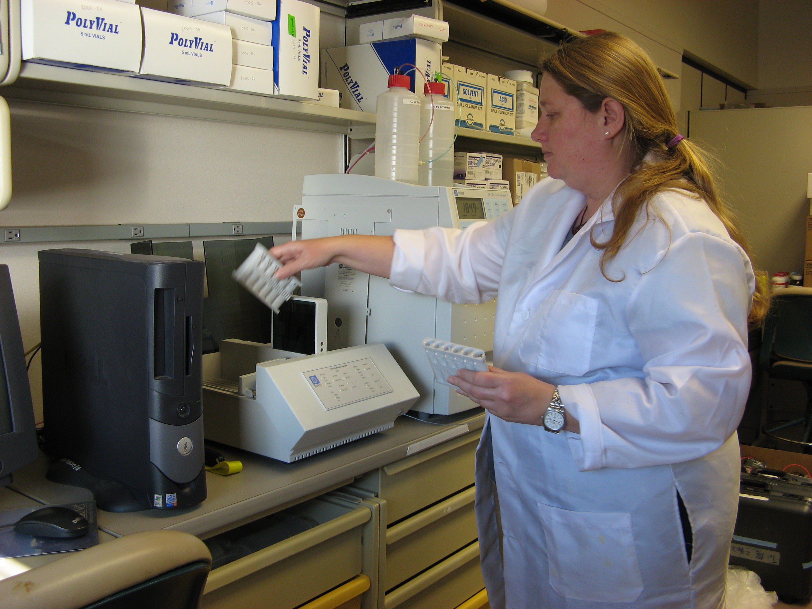 A woman in white lab coat works  in a science lab.