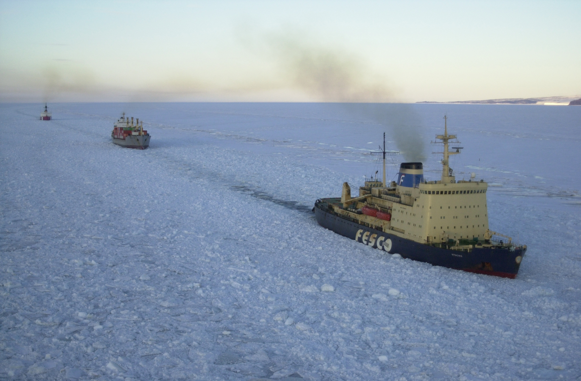 Three ships sail through sea ice.