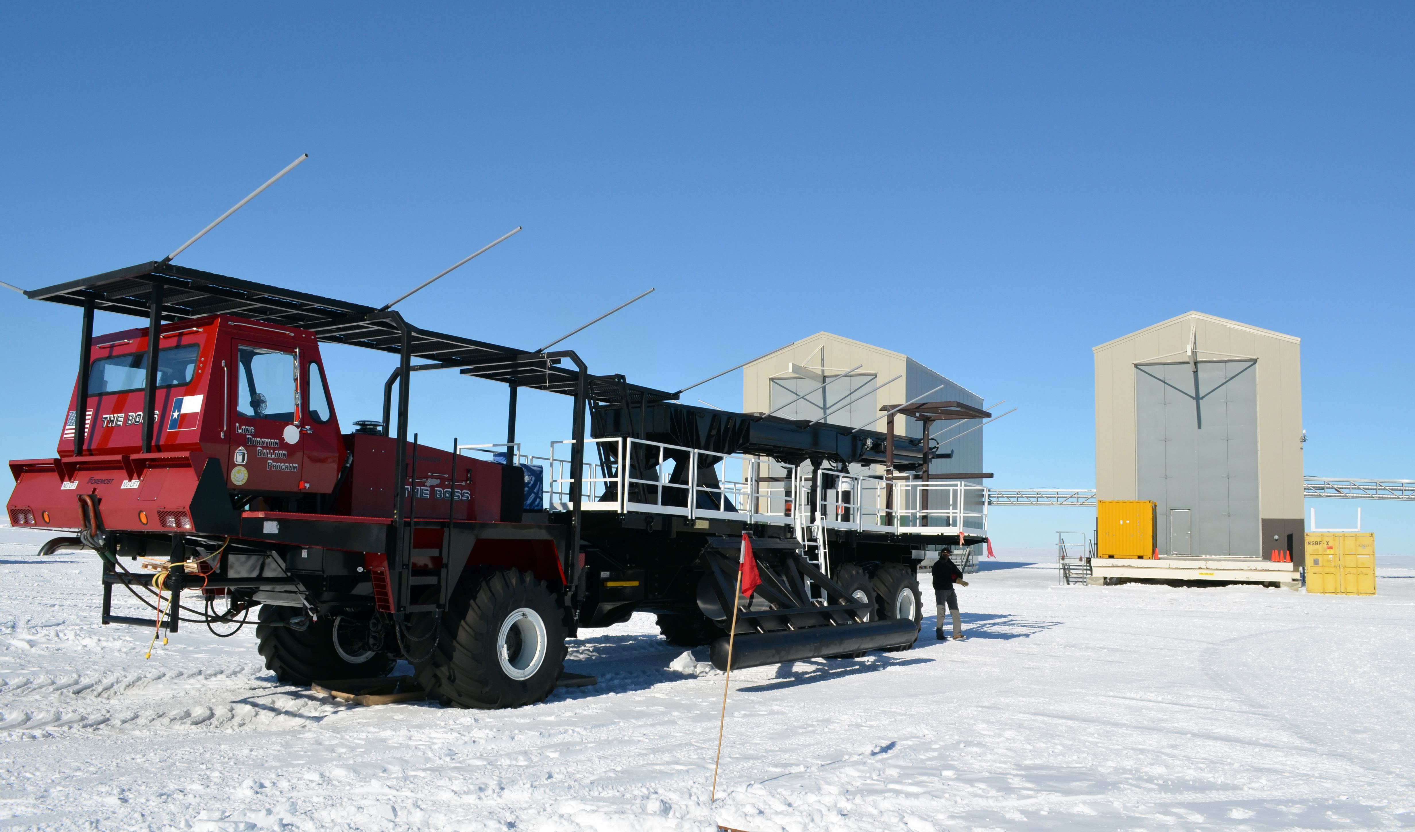 A large red truck sits in front of buildings.