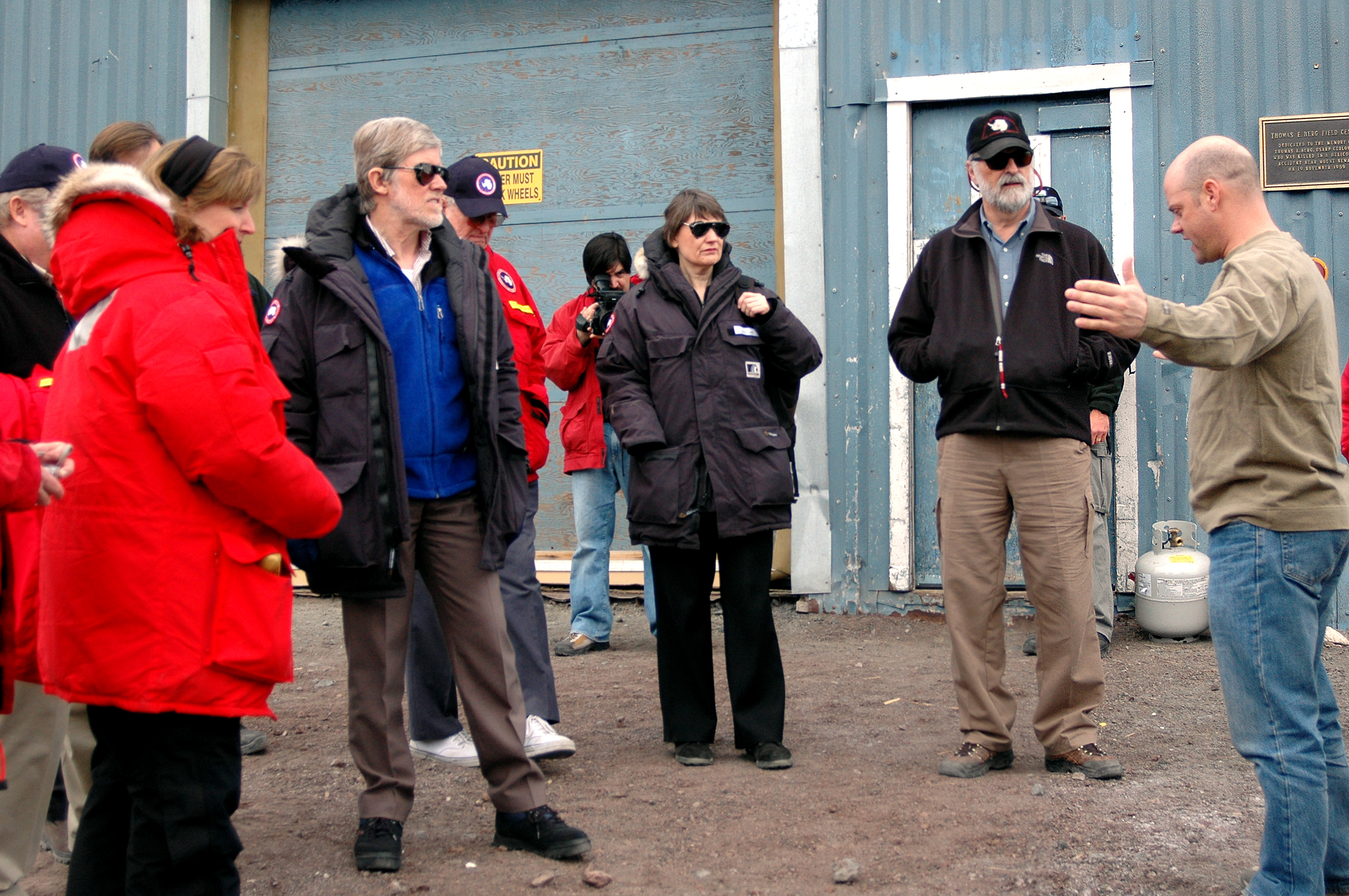 Person speaks to a group of people outside.