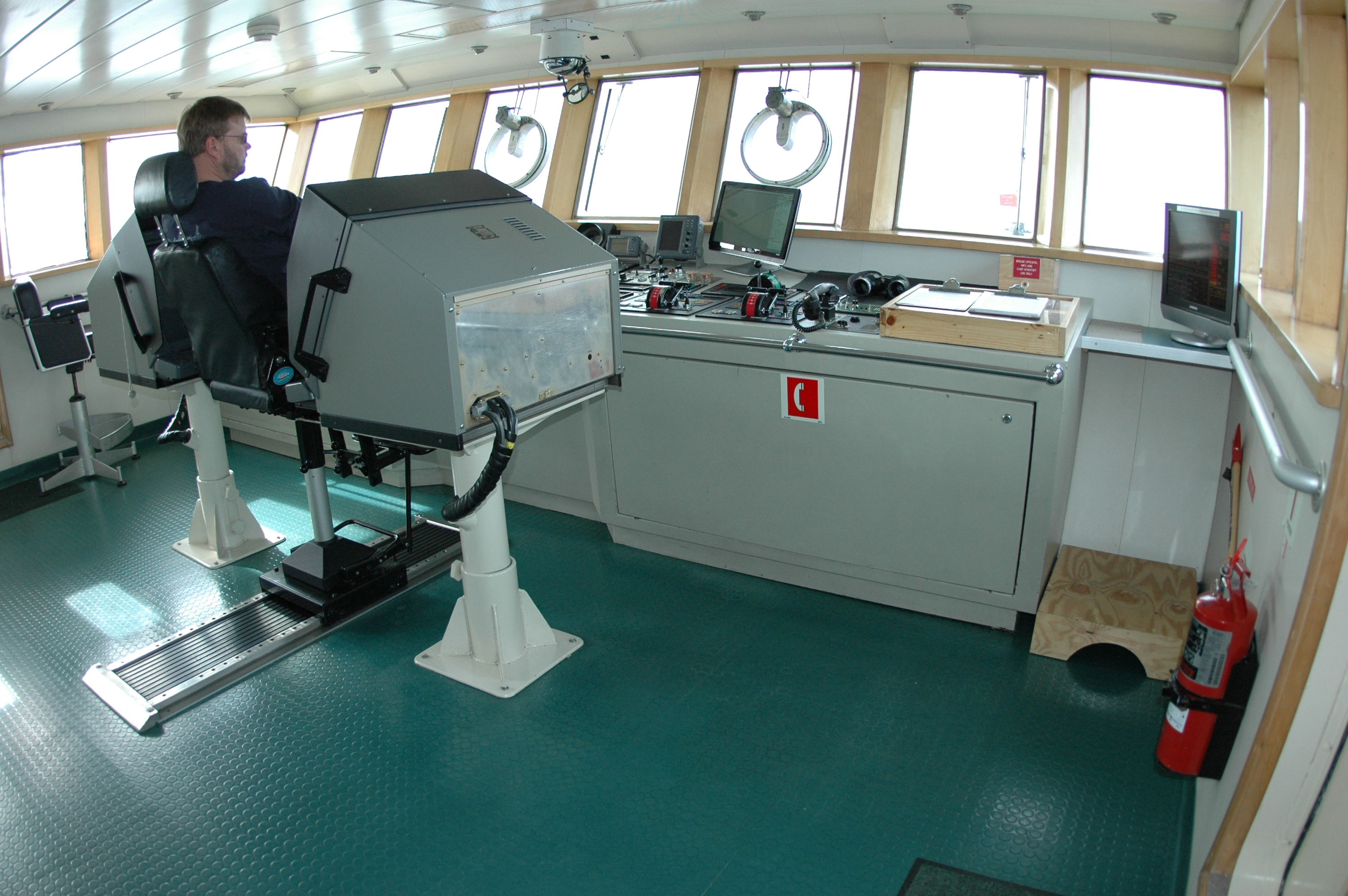 Man sits in ship bridge.