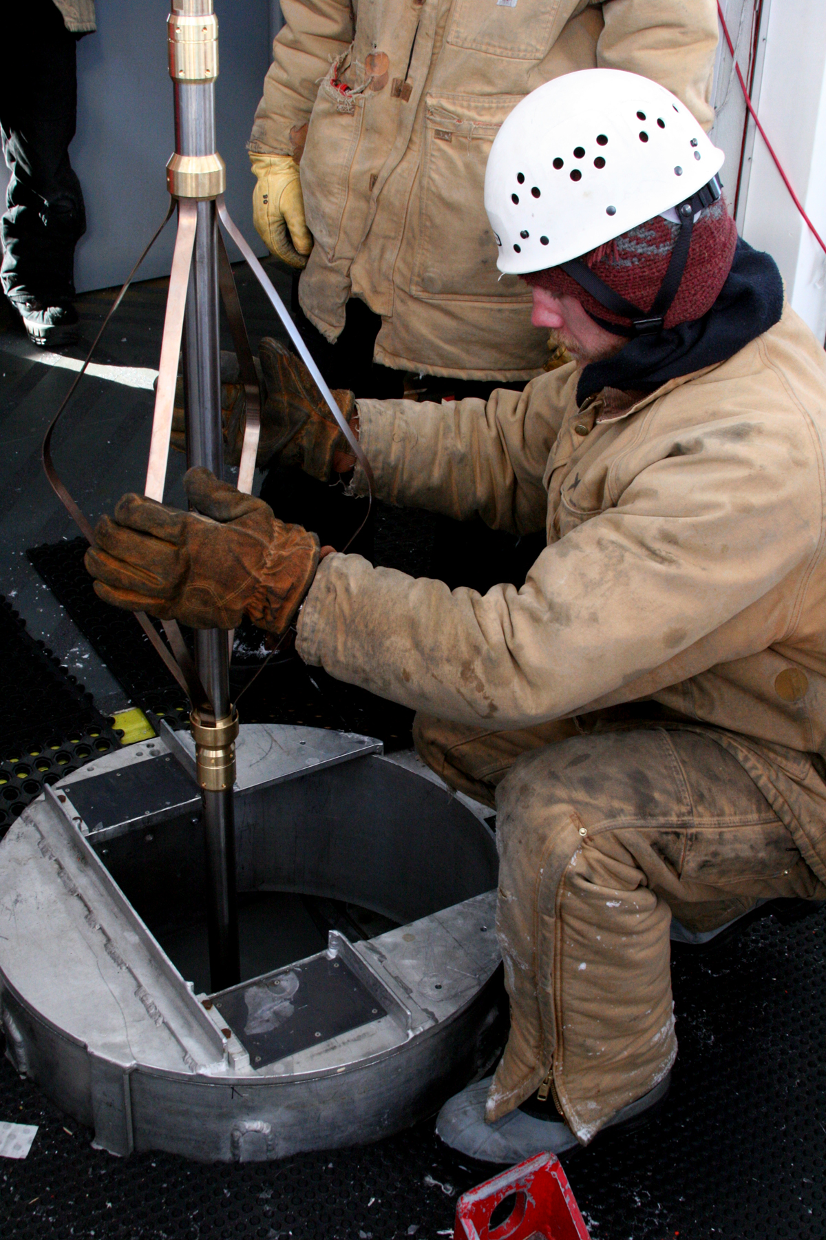 A man guides a device into a hole in the floor.