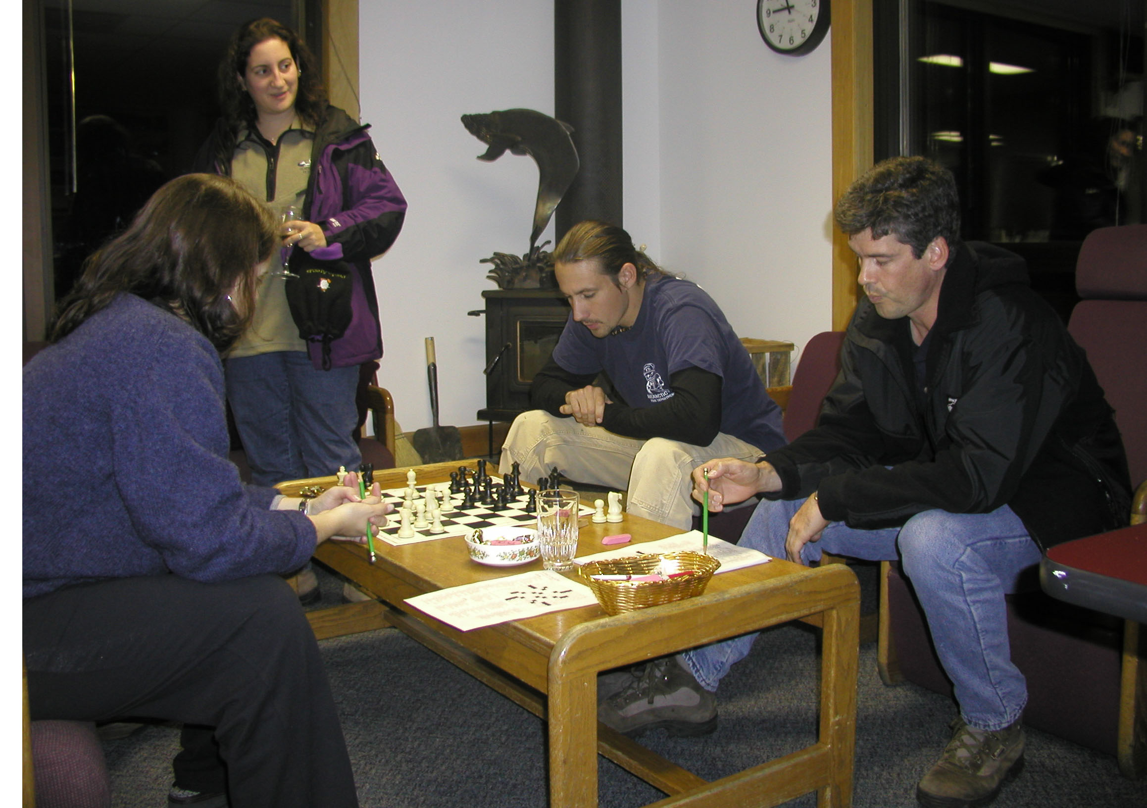 Four people in a lounge, two playing chess.