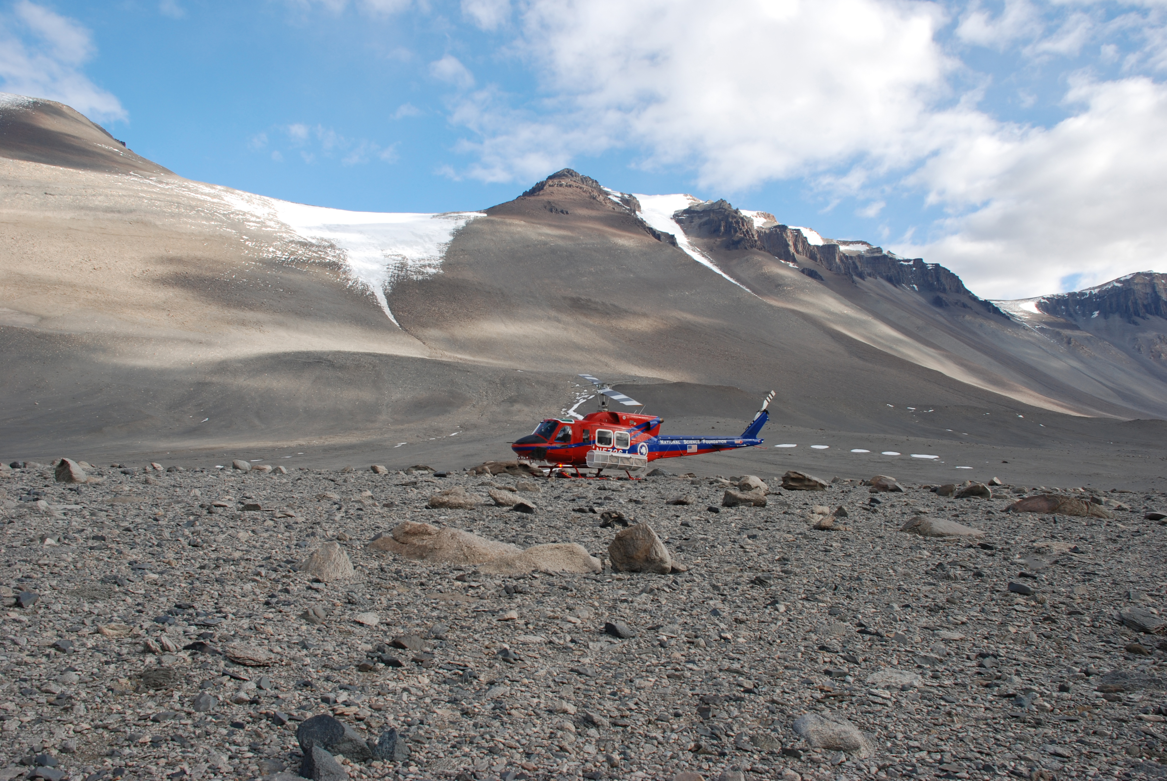 A helicopter at the bottom of a dry rocky valley.