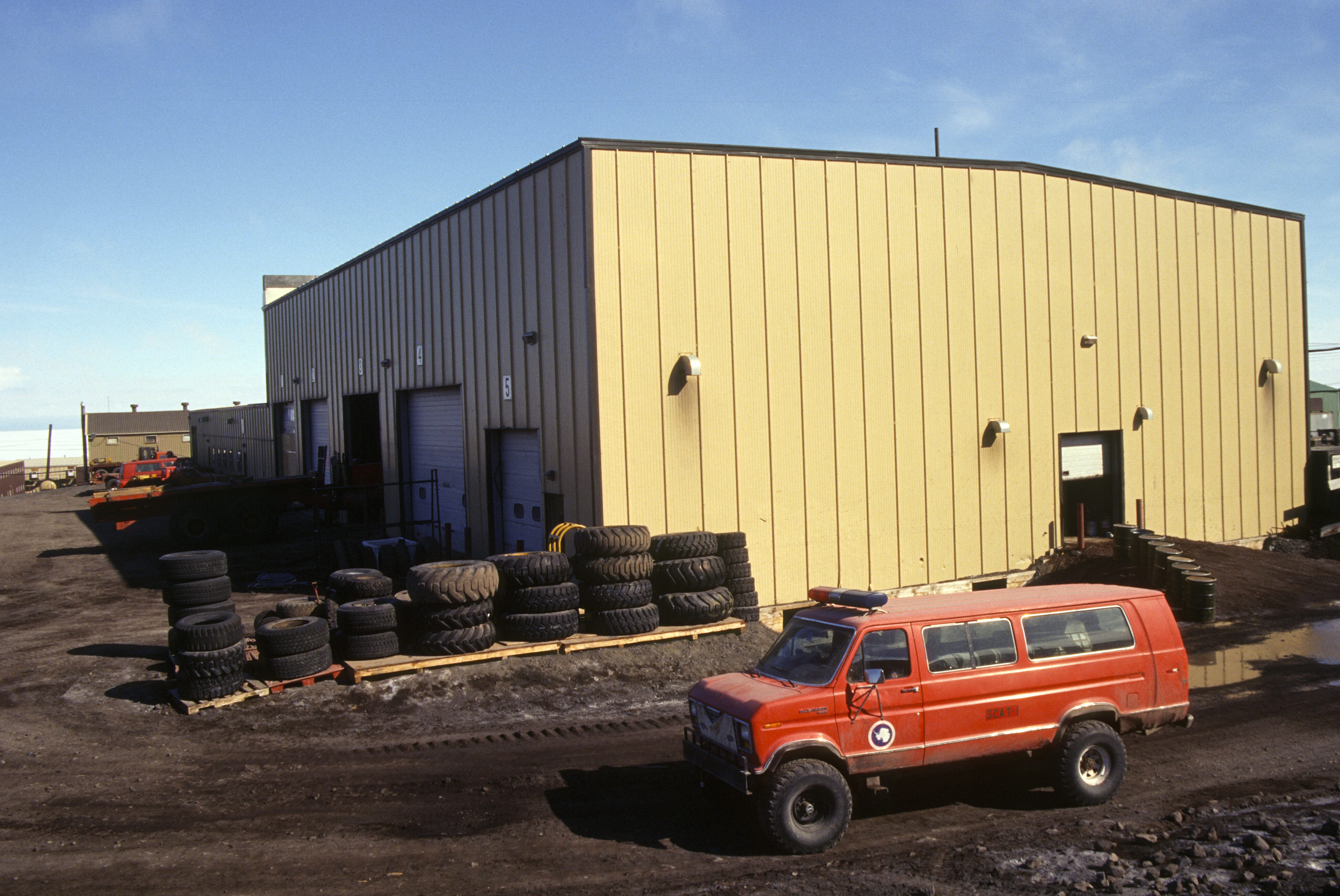 An orange passenger vehicle outside a cream-colored building.