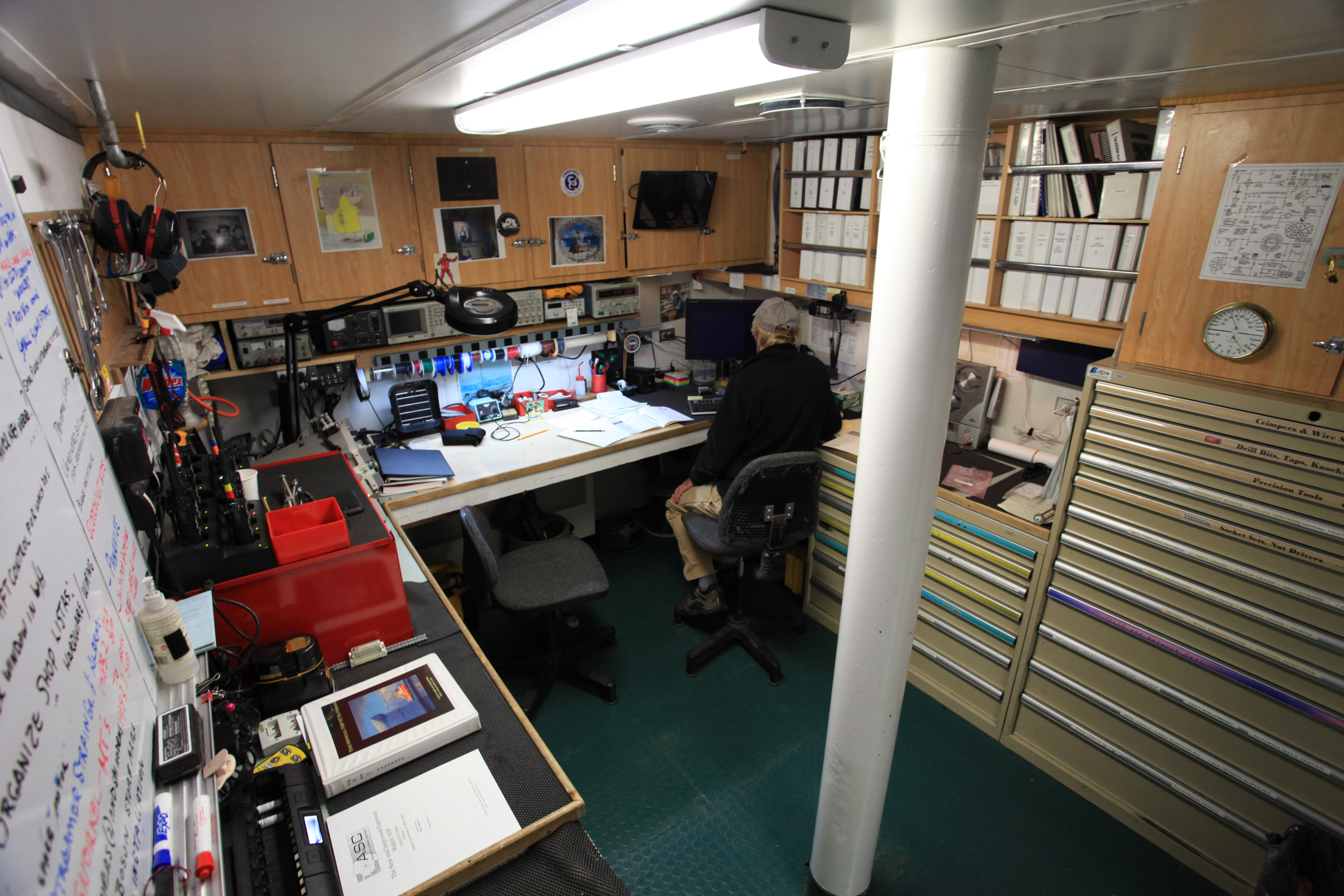 A person works on a computer in an office space on a ship.