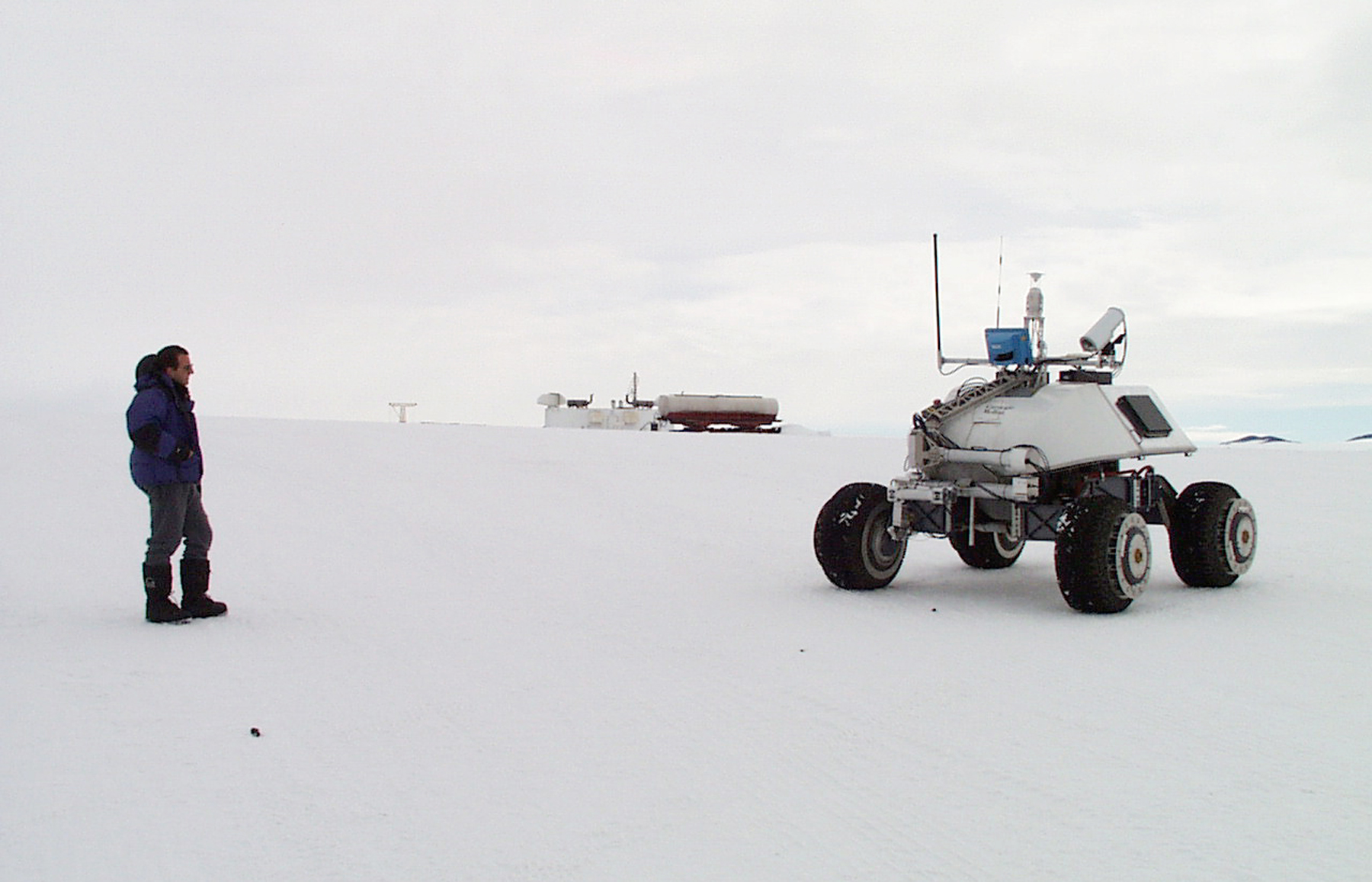 A person looks at a robotic machine on four wheels.