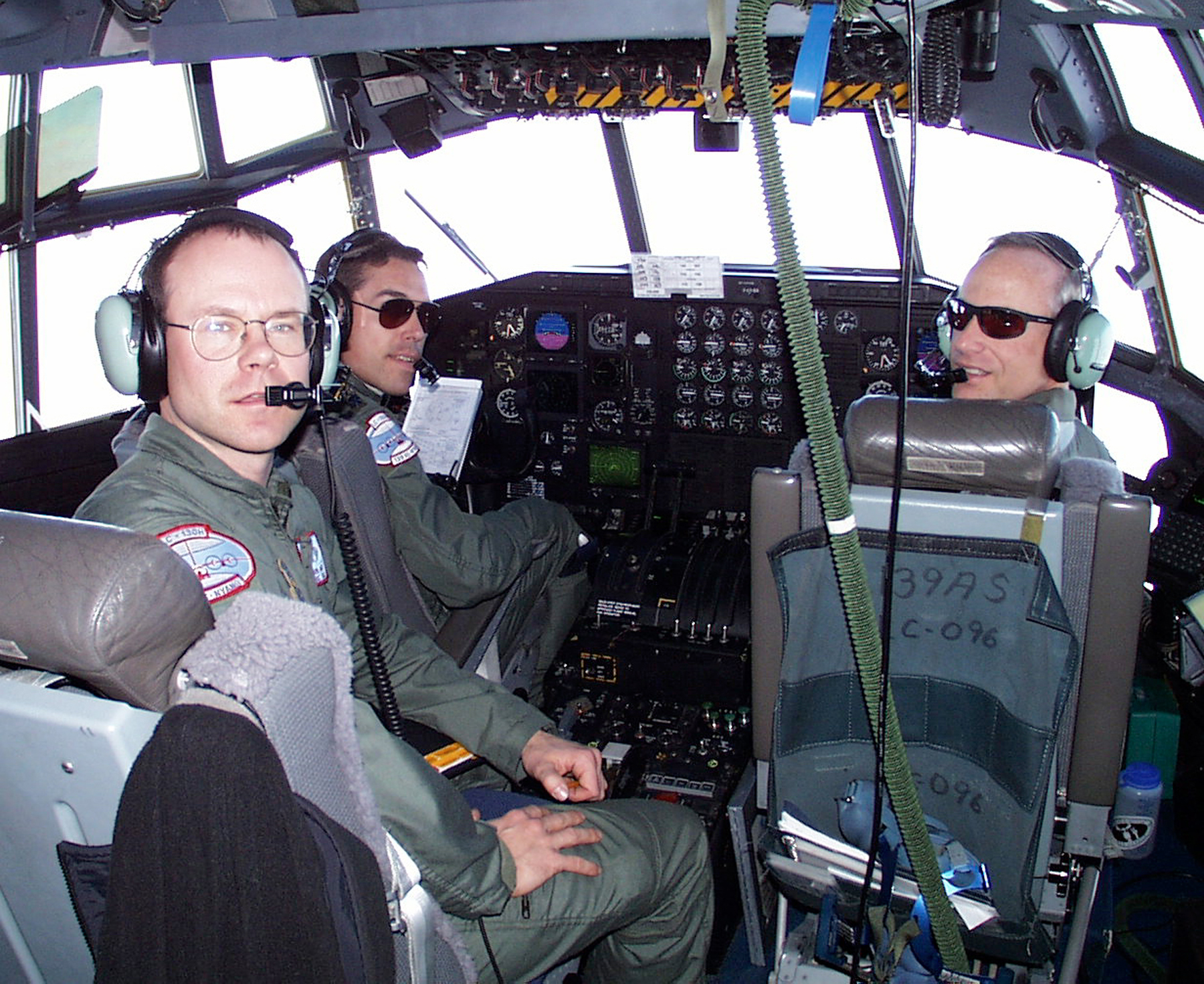 The crew inside a cockpit turn to face the camera.