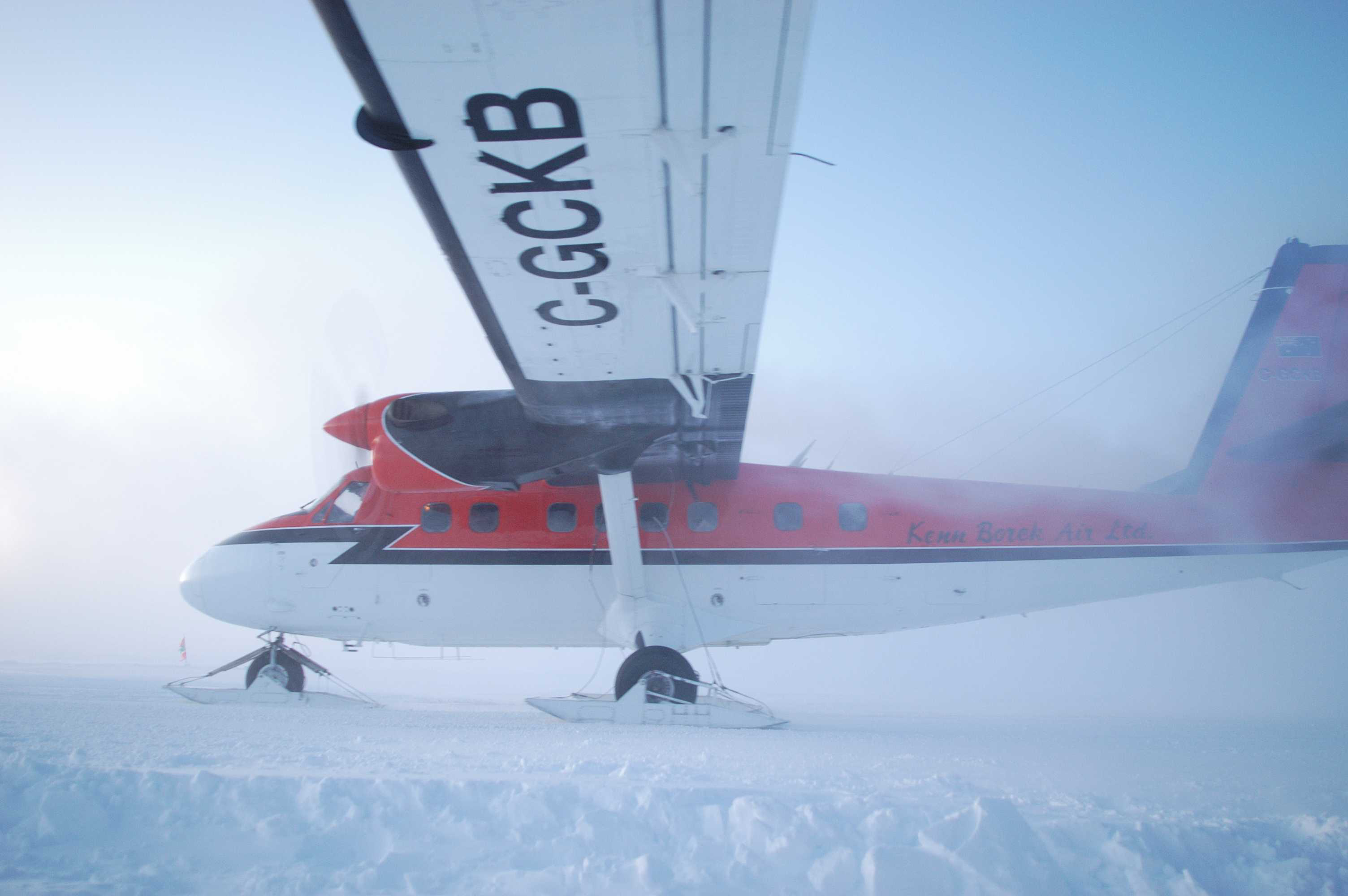 A twin-engine airplane, with skis, sits on snow.