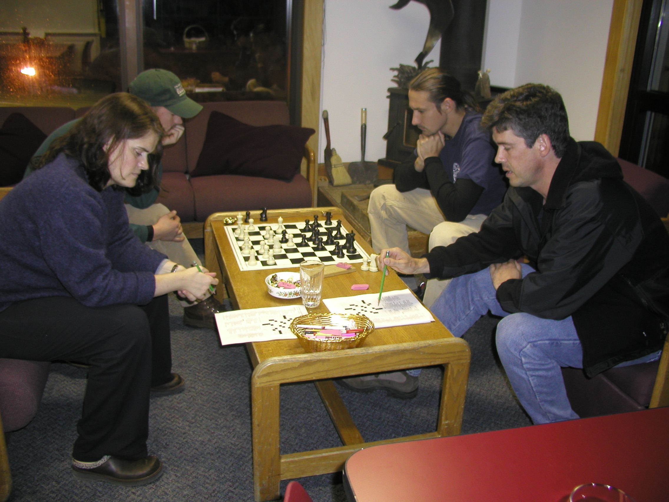 Four people in a lounge, two playing chess.