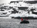 People ride in a rubber boat in icy water.