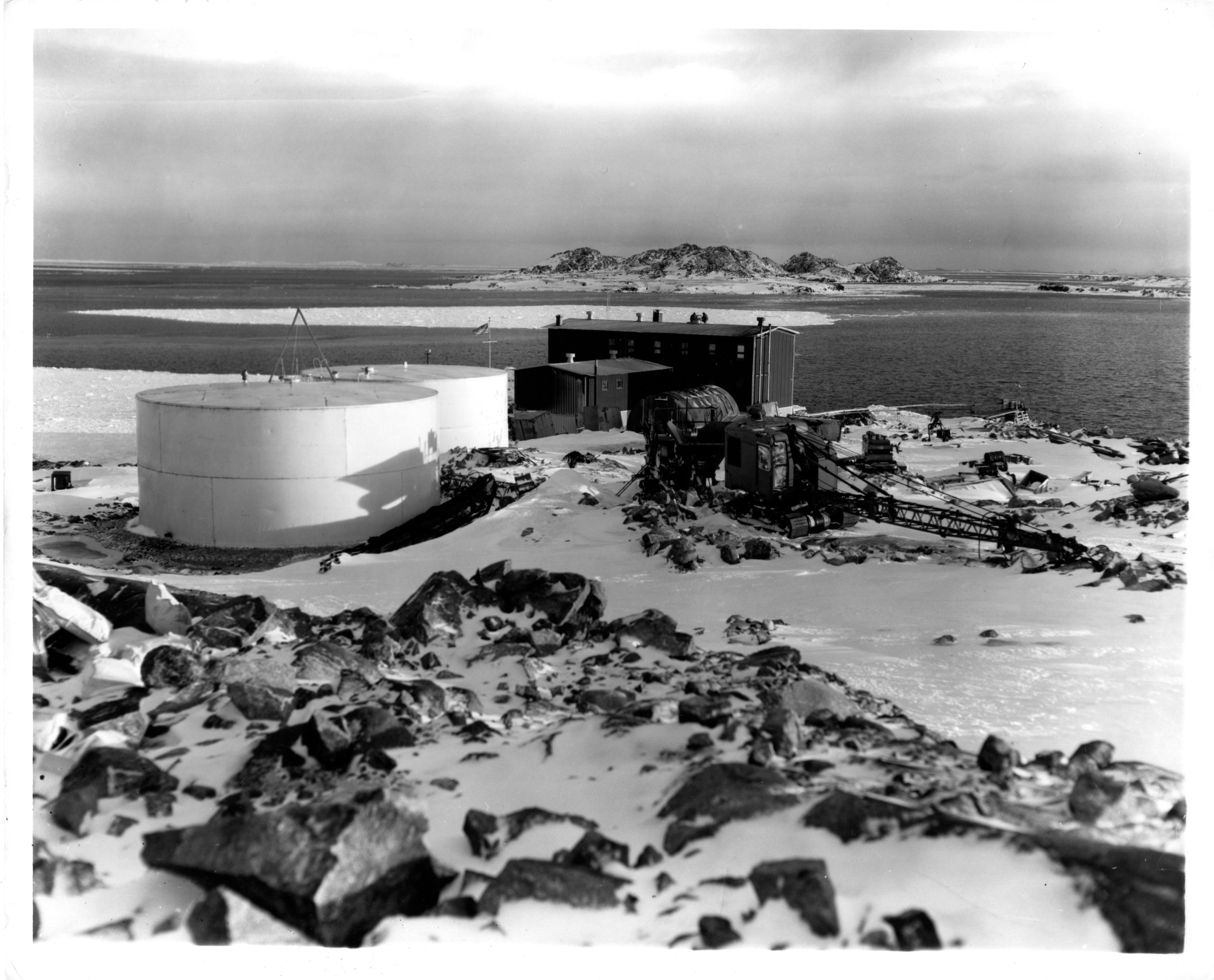 Fuel storage tank along rocky coastline.