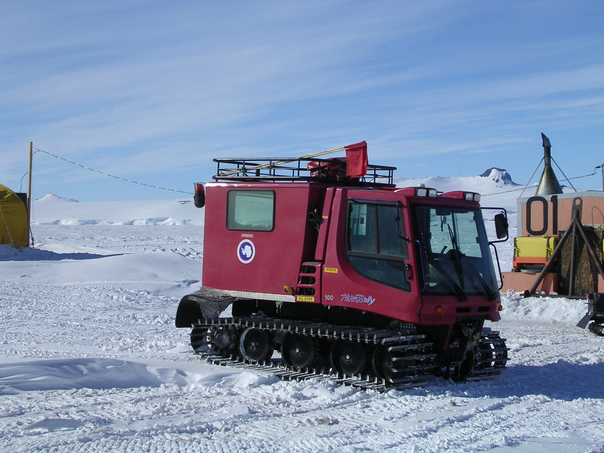 A red truck sits on the snow.