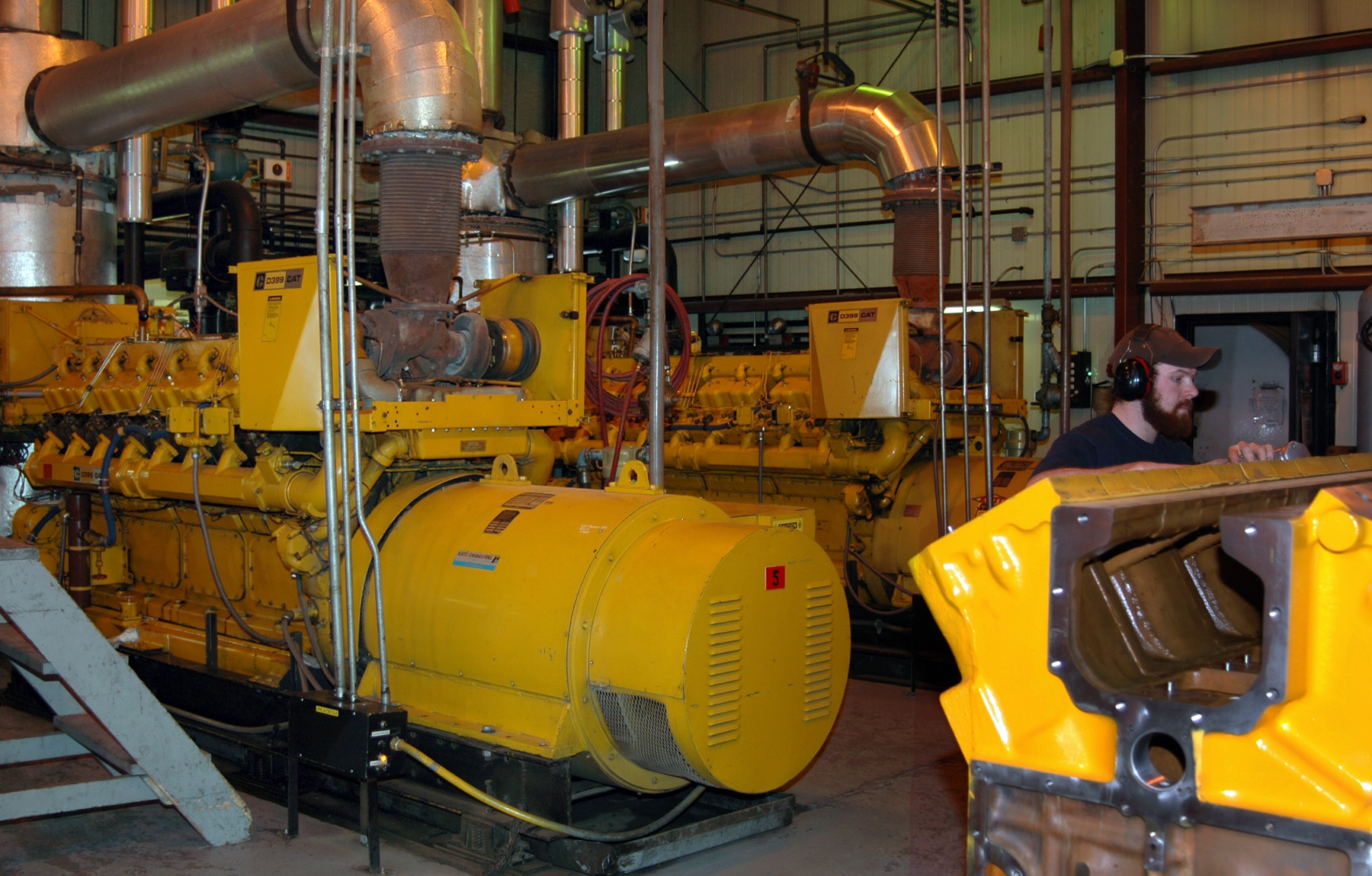 Man works in front of large, yellow equipment