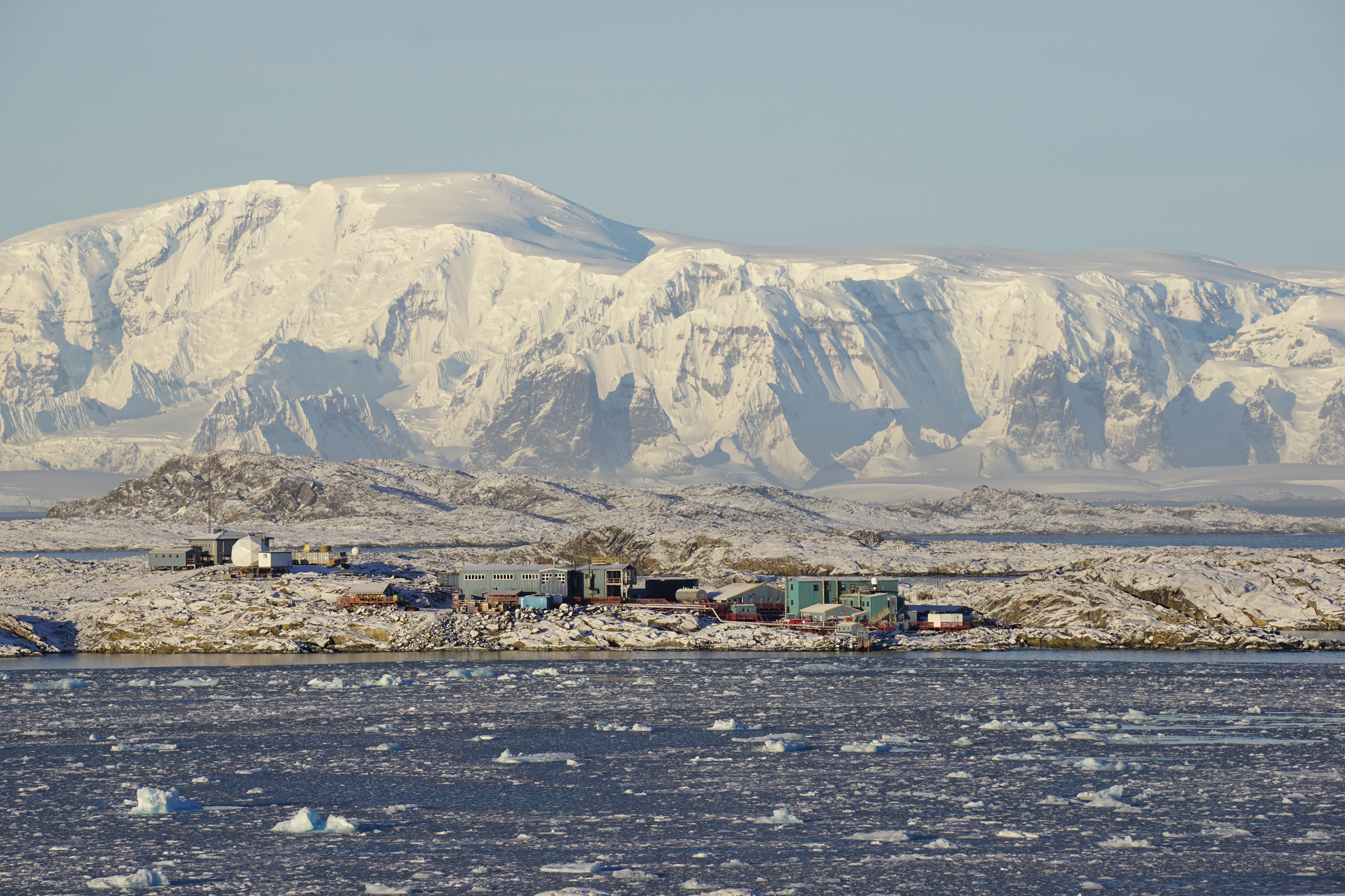 Buildings by the ocean with mountains in the distance.