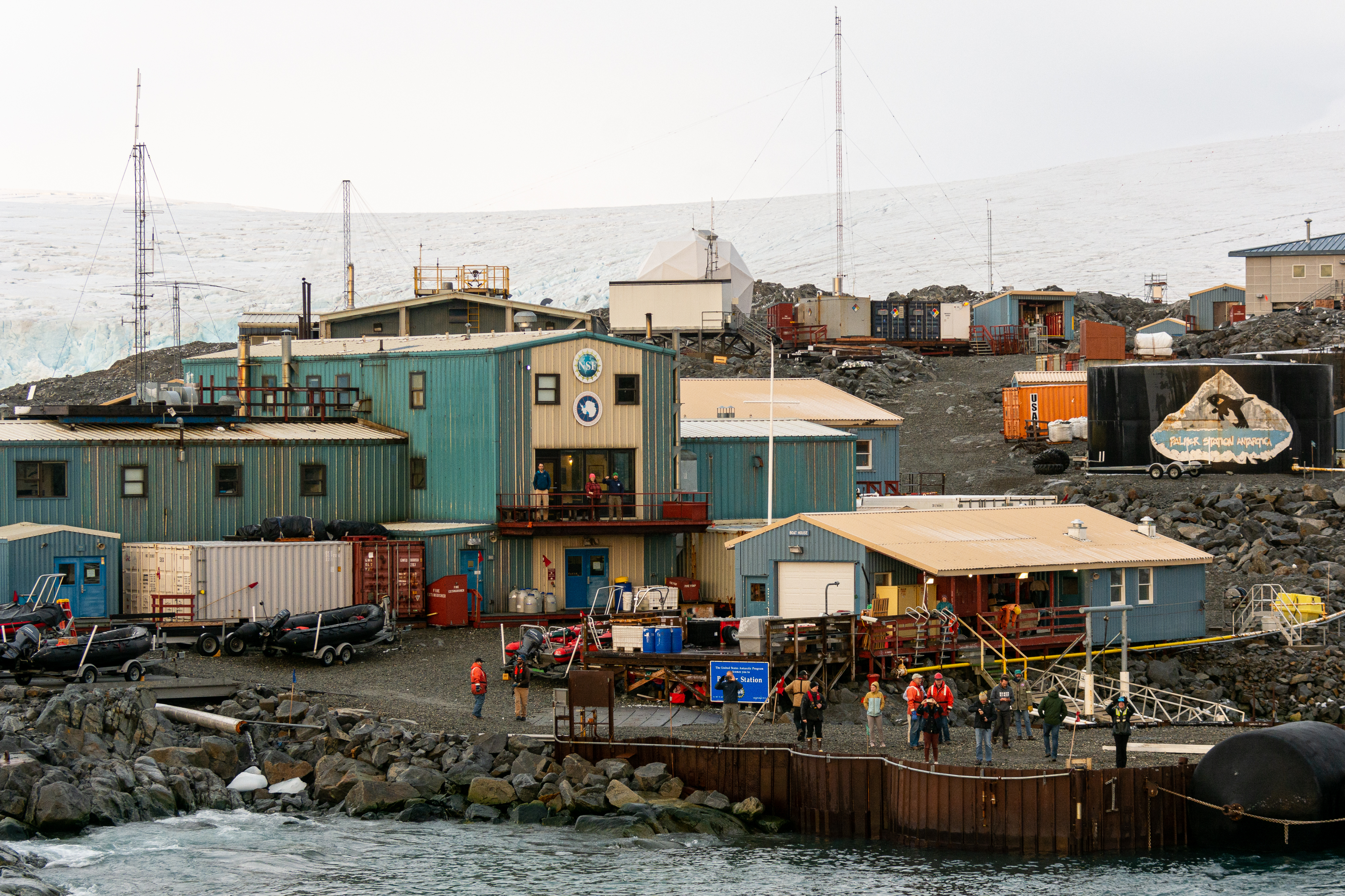 People gather on a pier in front of buildings. 