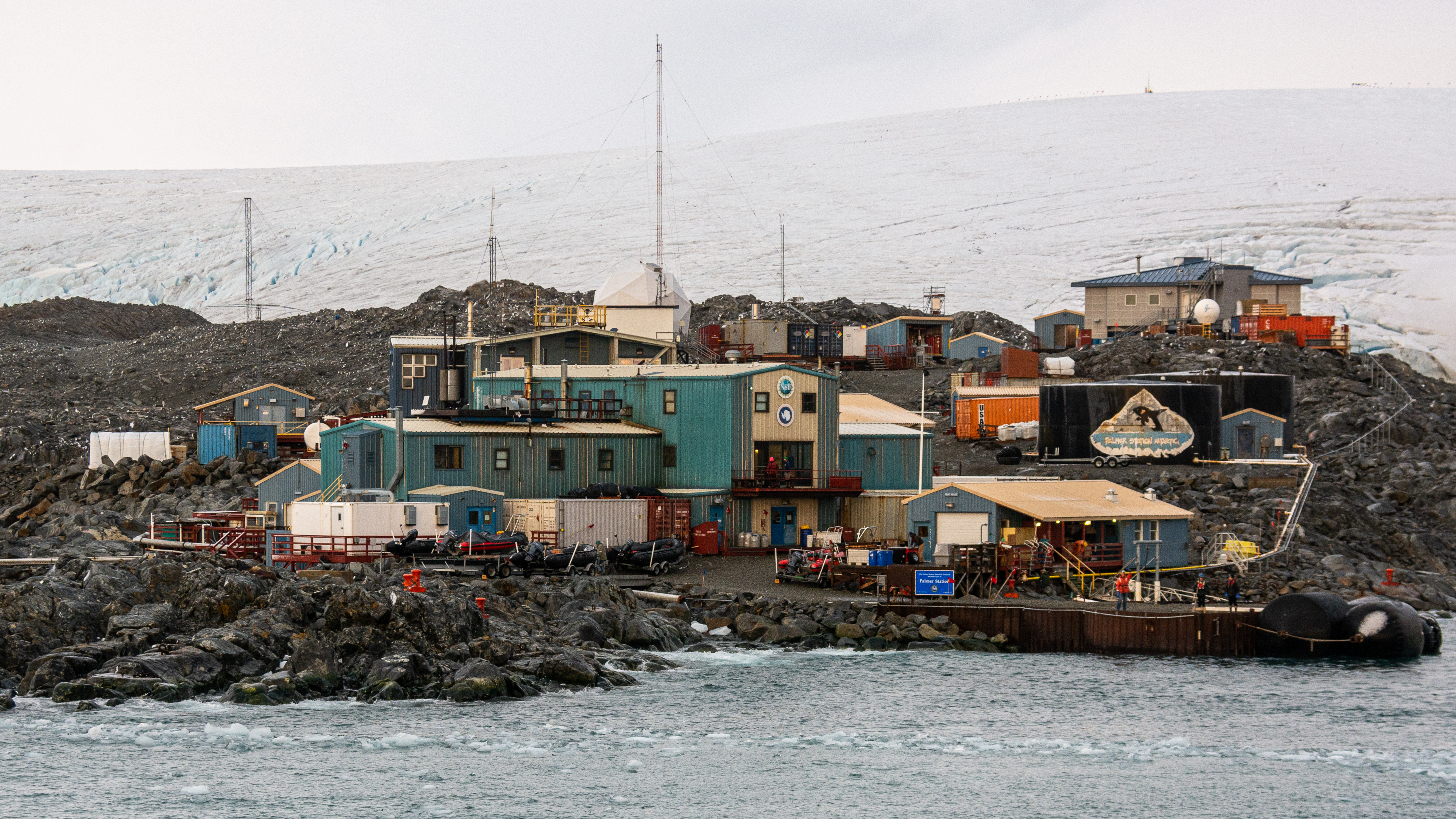 People gather on a pier in front of buildings. 