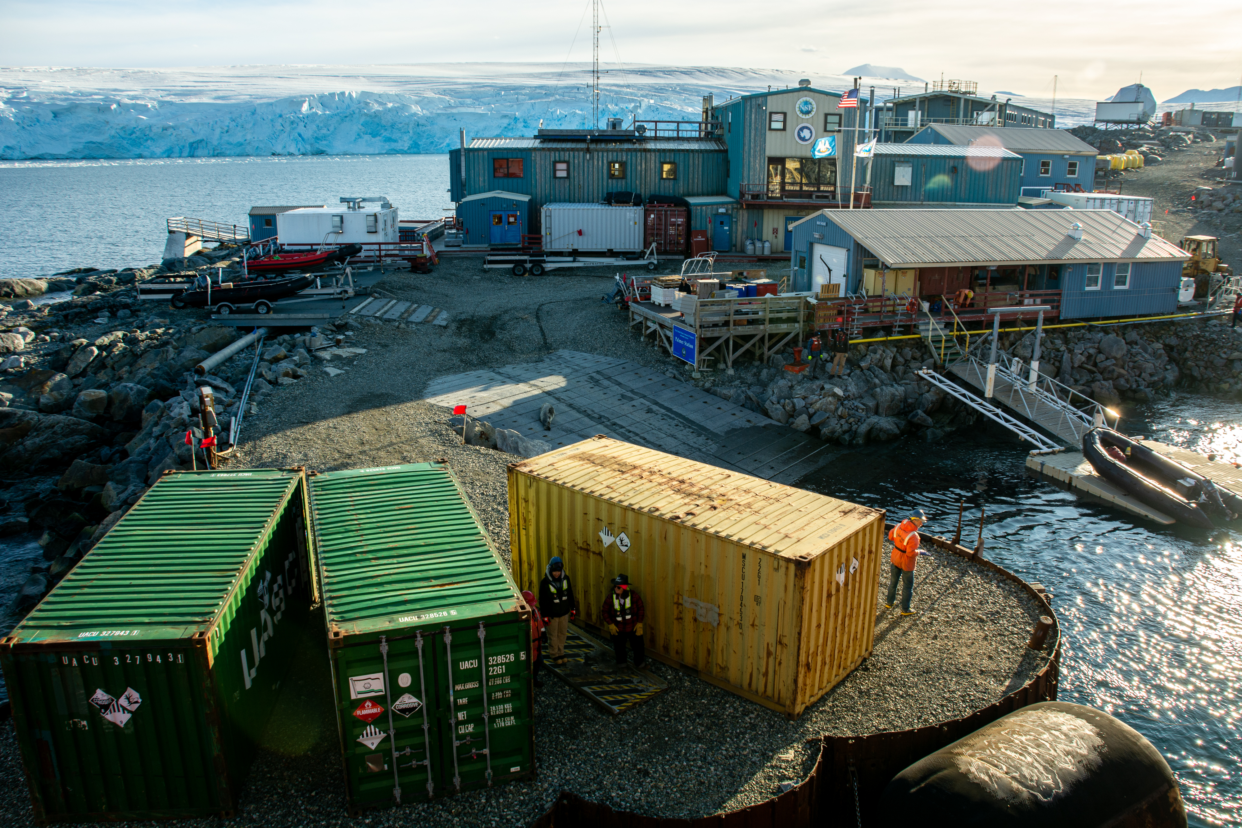 Shipping containers positioned on a pier with buildings in the background. 