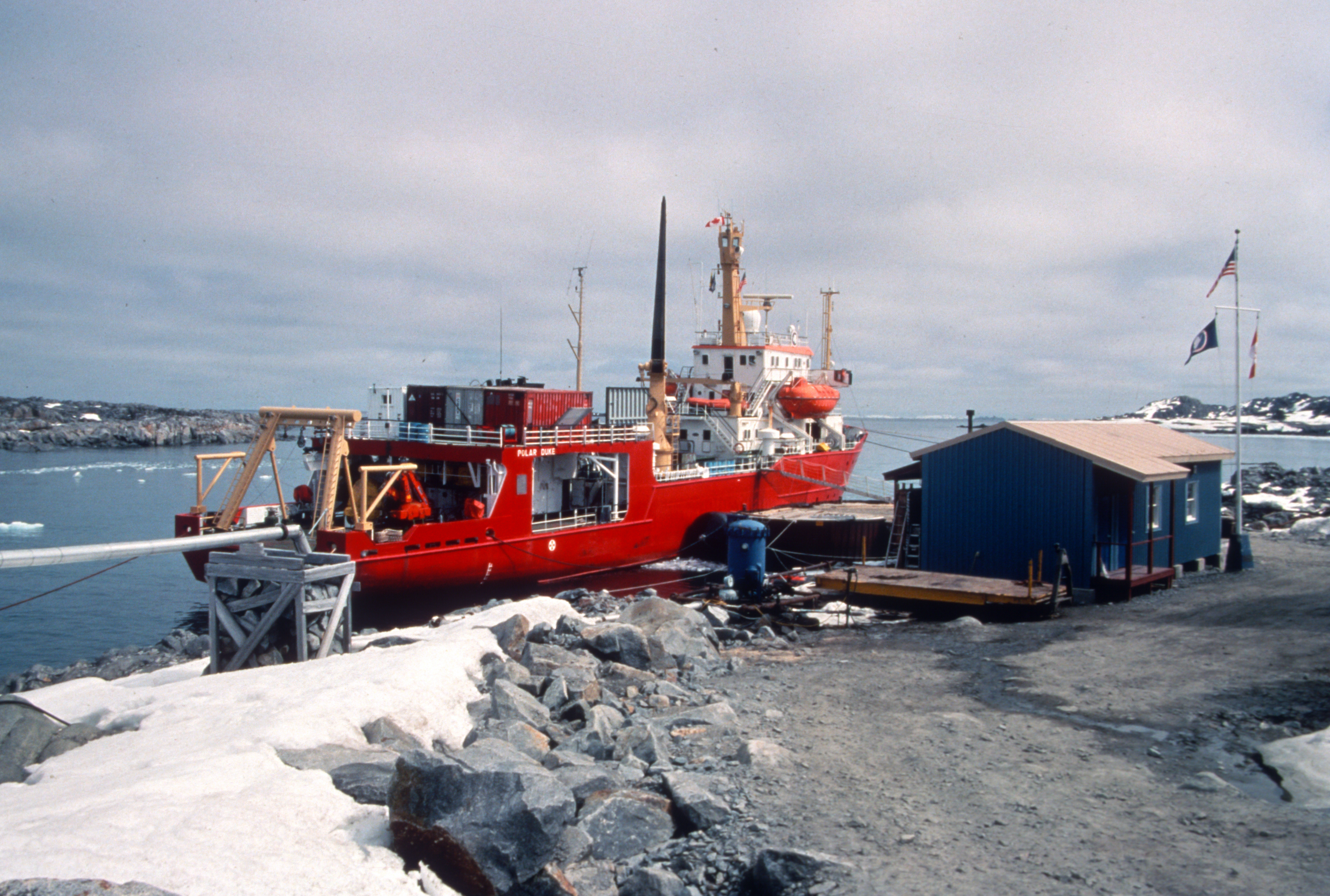 A ship docked next to a small building.