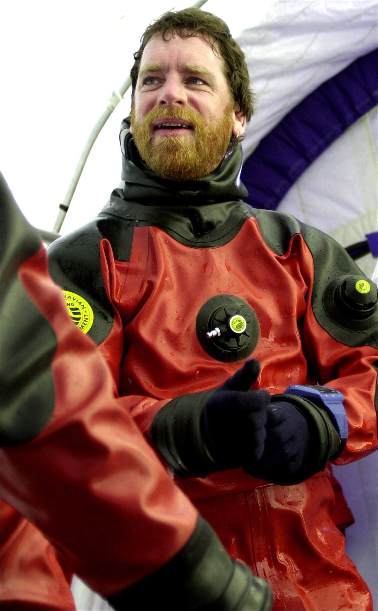A bearded man dressed in a black and red scuba diving suit.