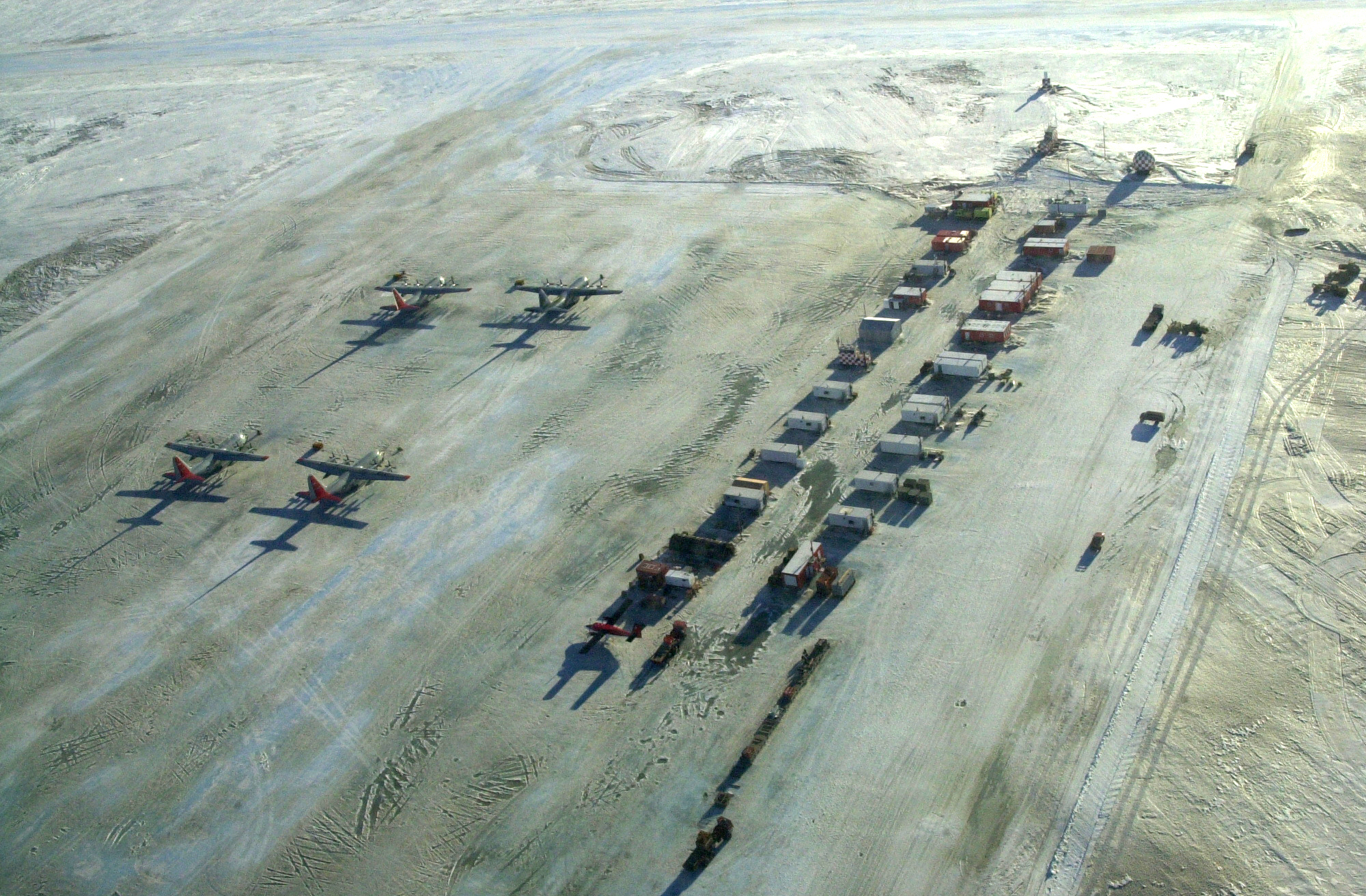 Aerial of airplanes and small buildings on ice.