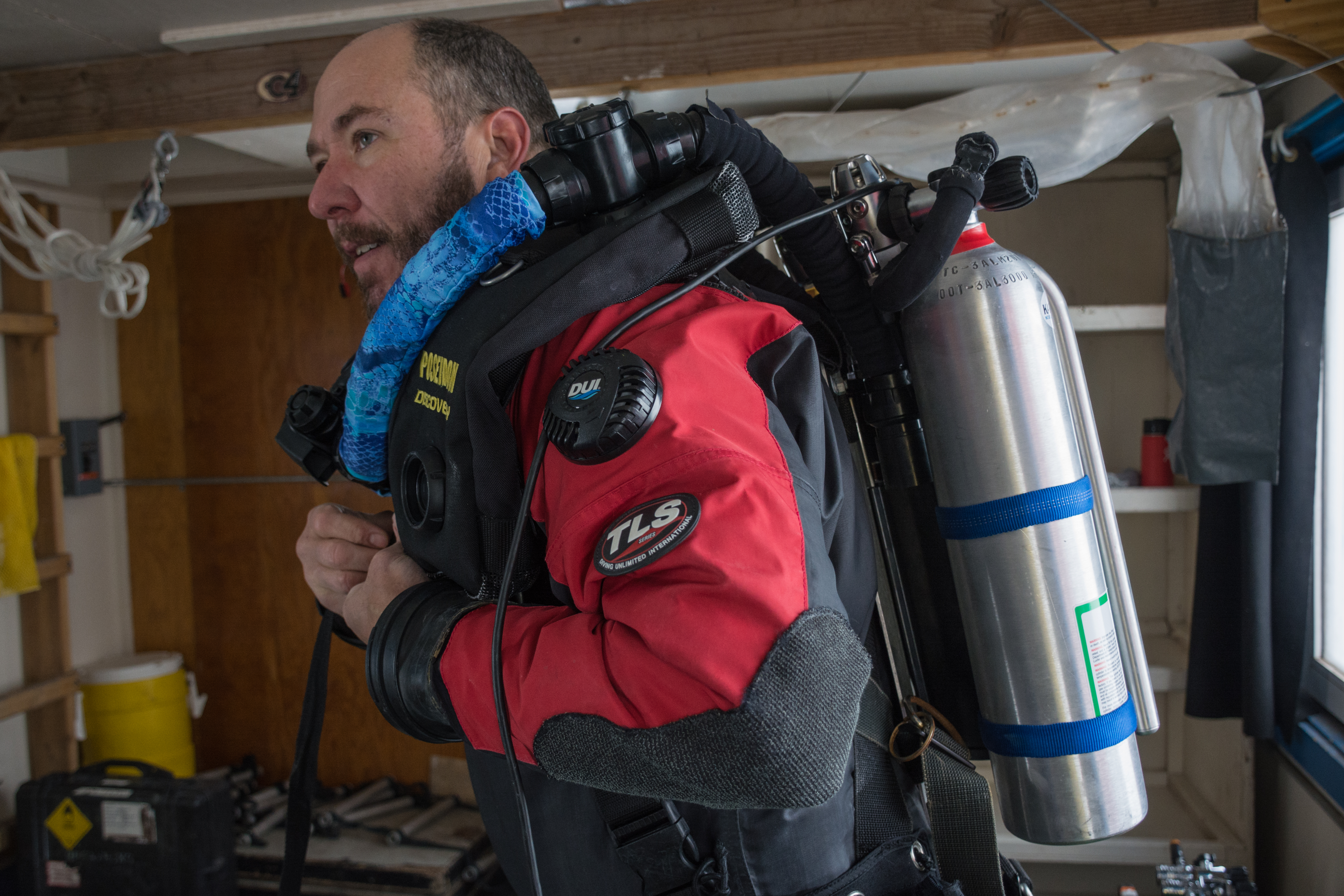 A scuba diver puts on his scuba tank.