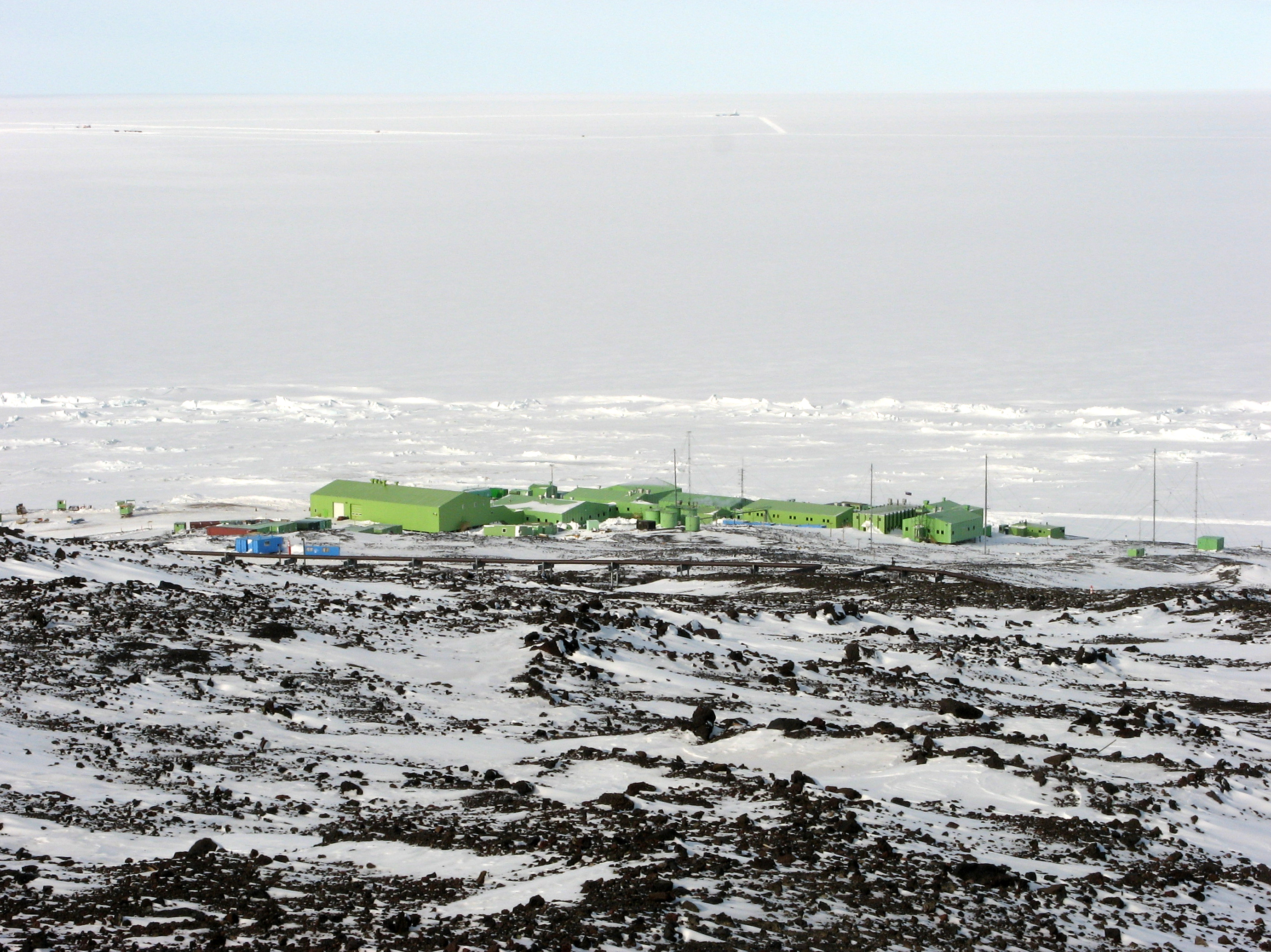 Cluster of green buildings sits near ice field.