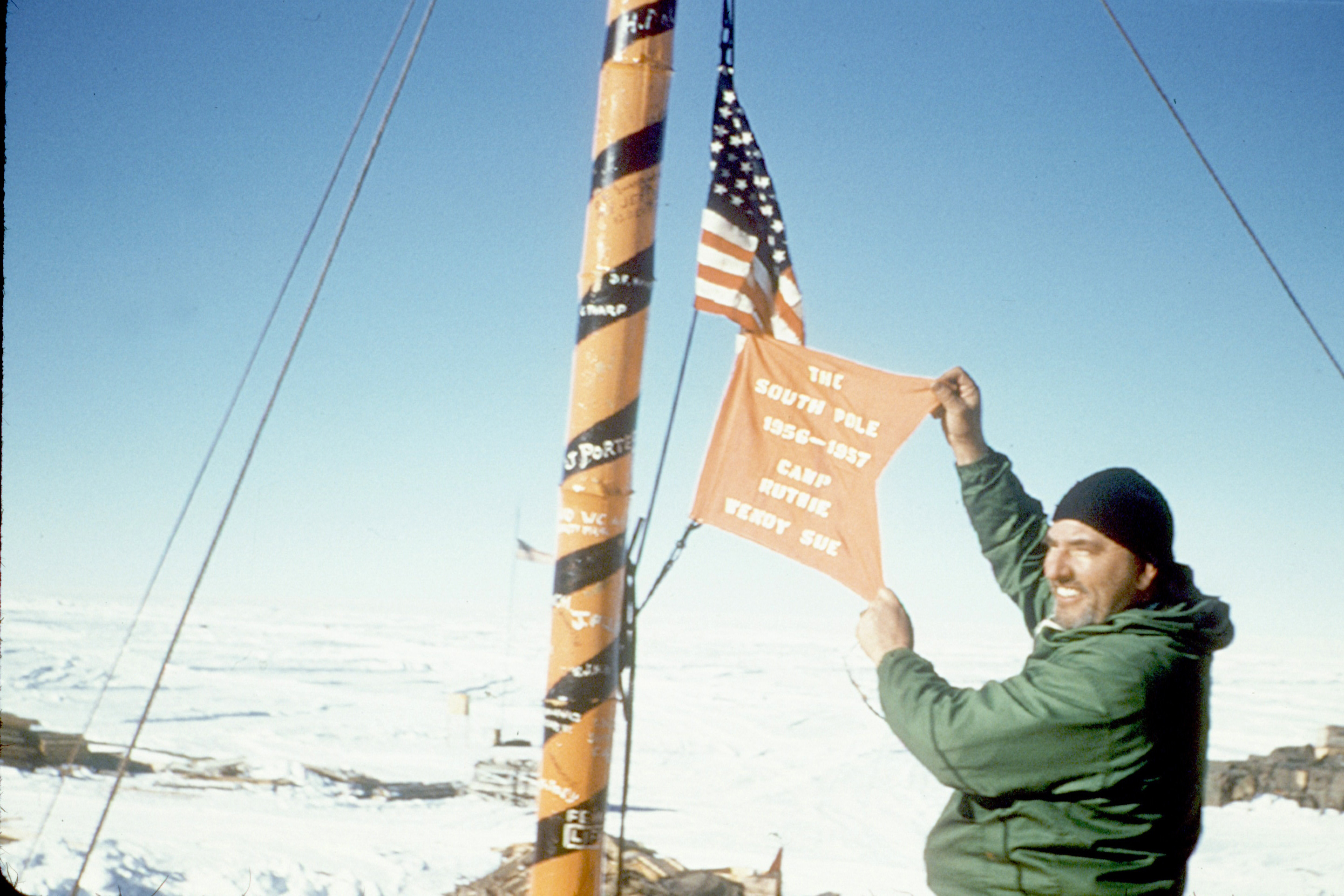 Man holds out flag at flag pole.