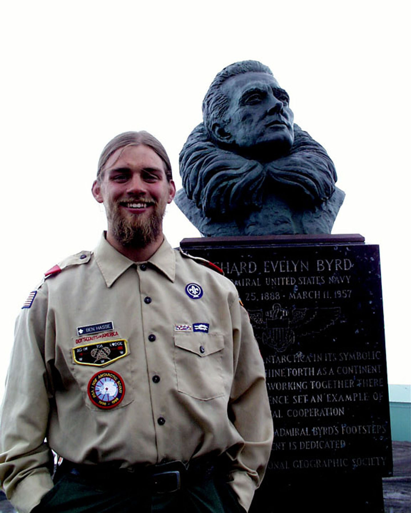 A man stands near a bust of Admiral Byrd.