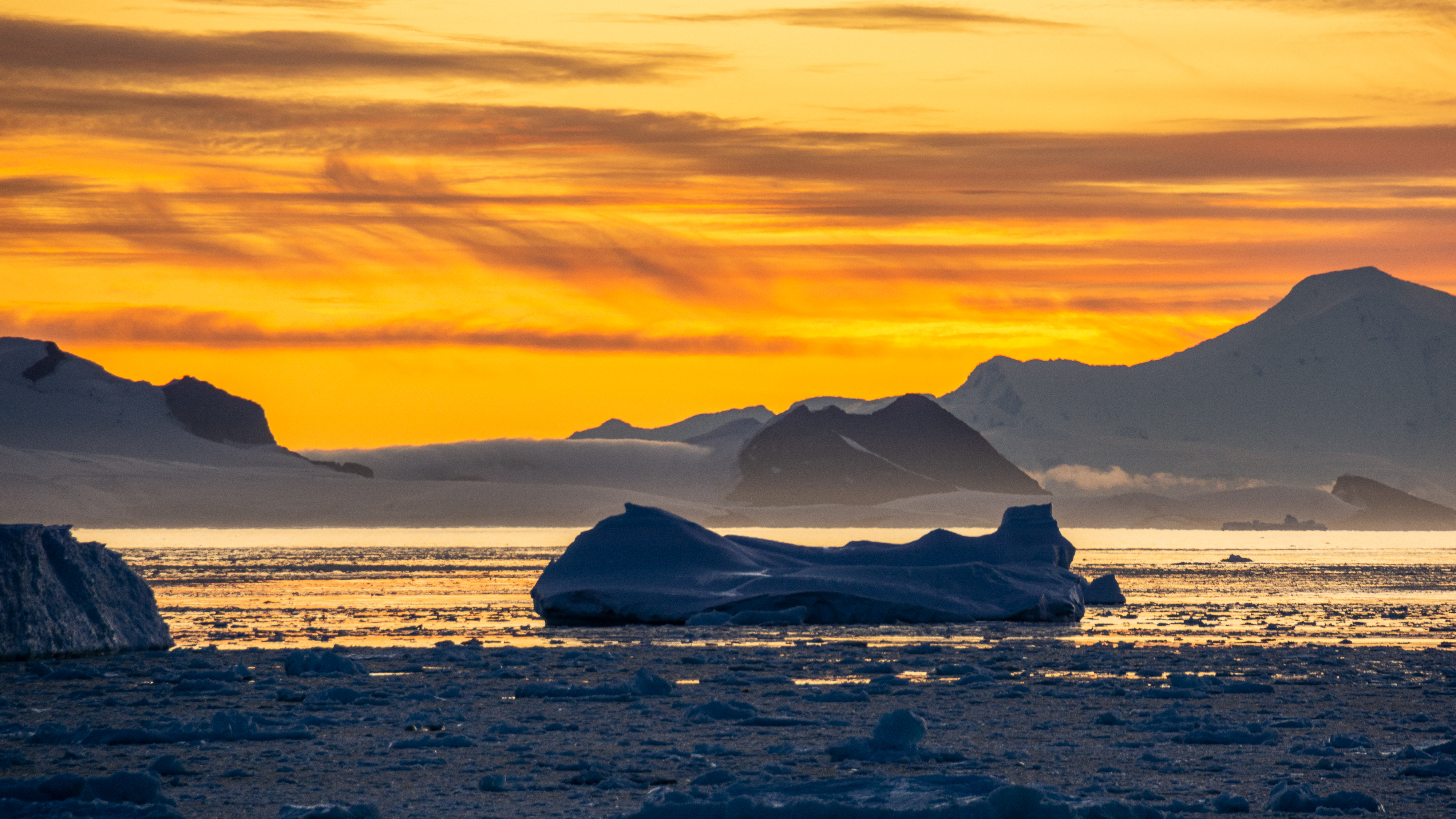 The sunsets over an iceberg-filled harbor.