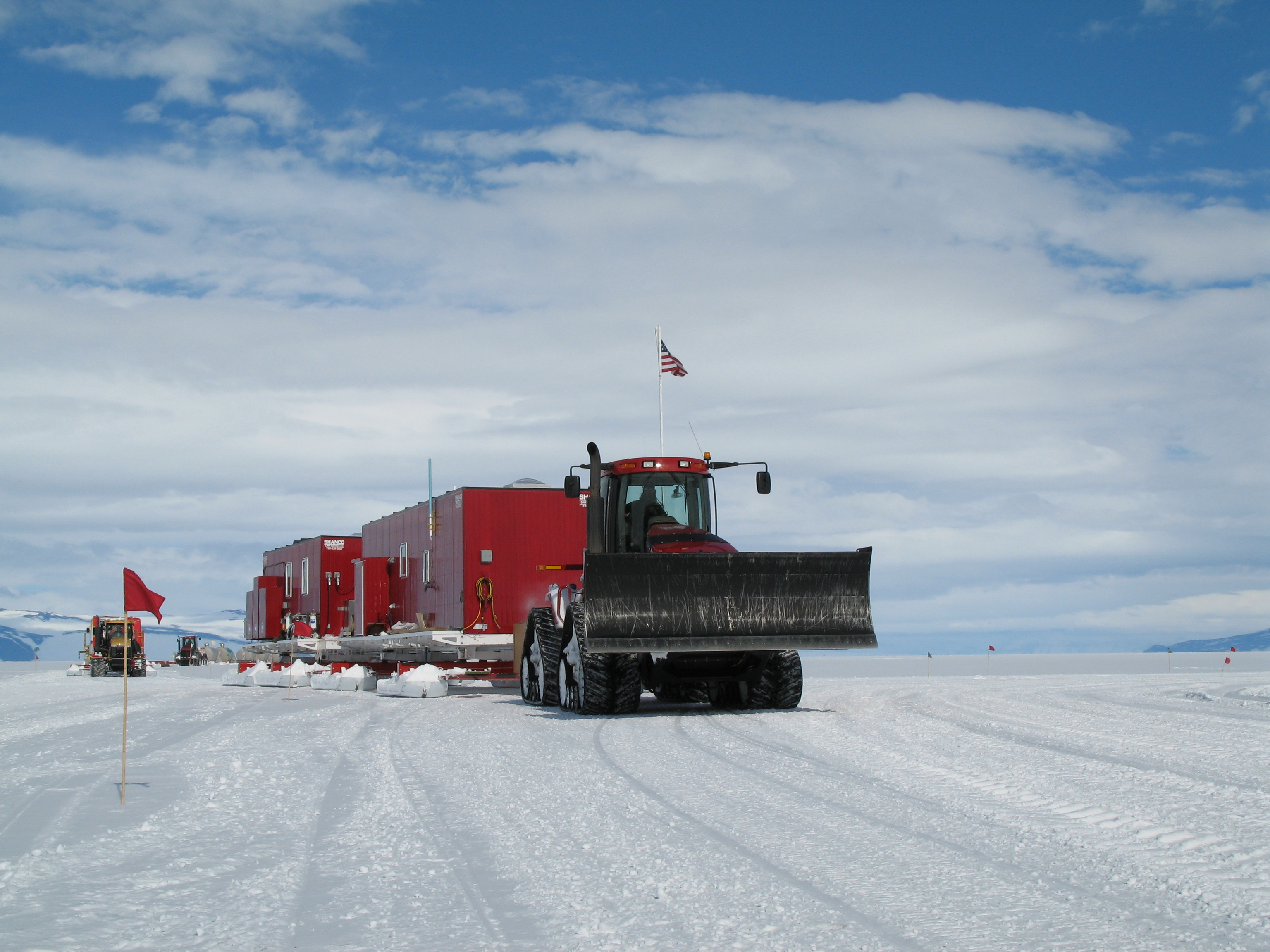 A tractor pulling large sleds across snow.