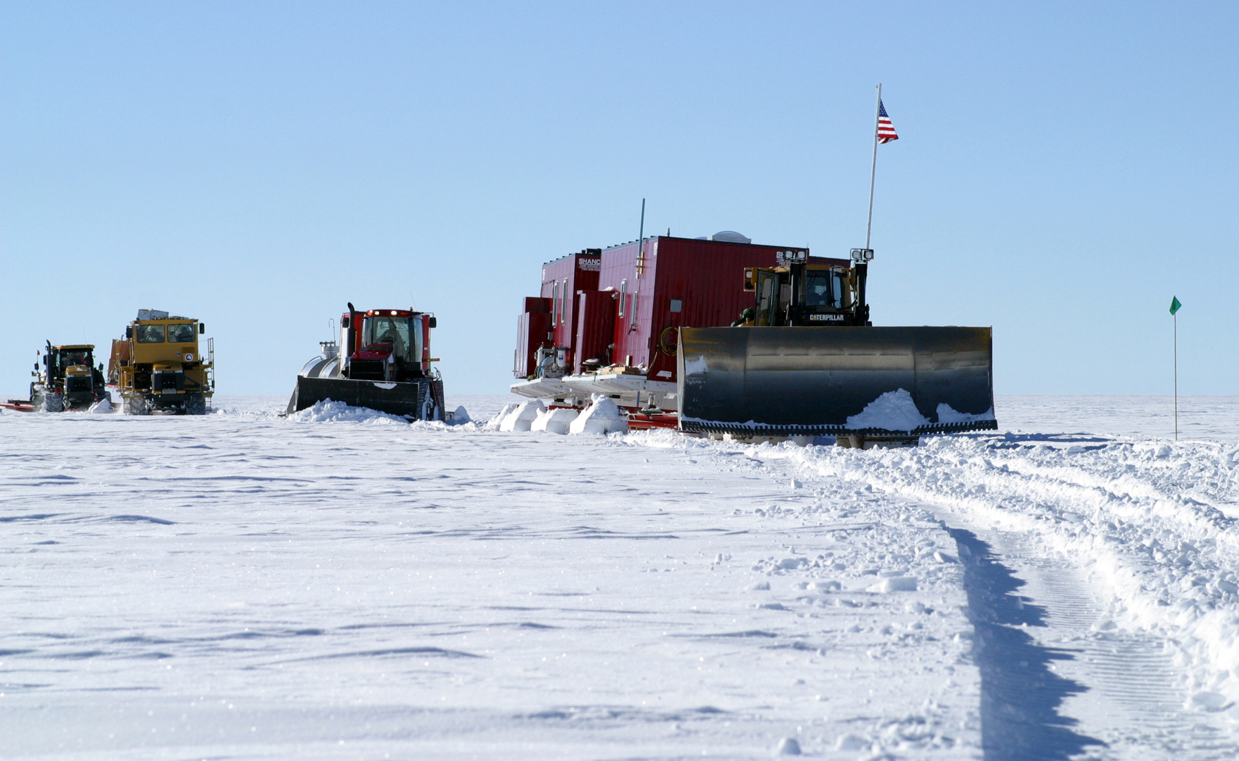 Operators drive heavy equipment through the snow.