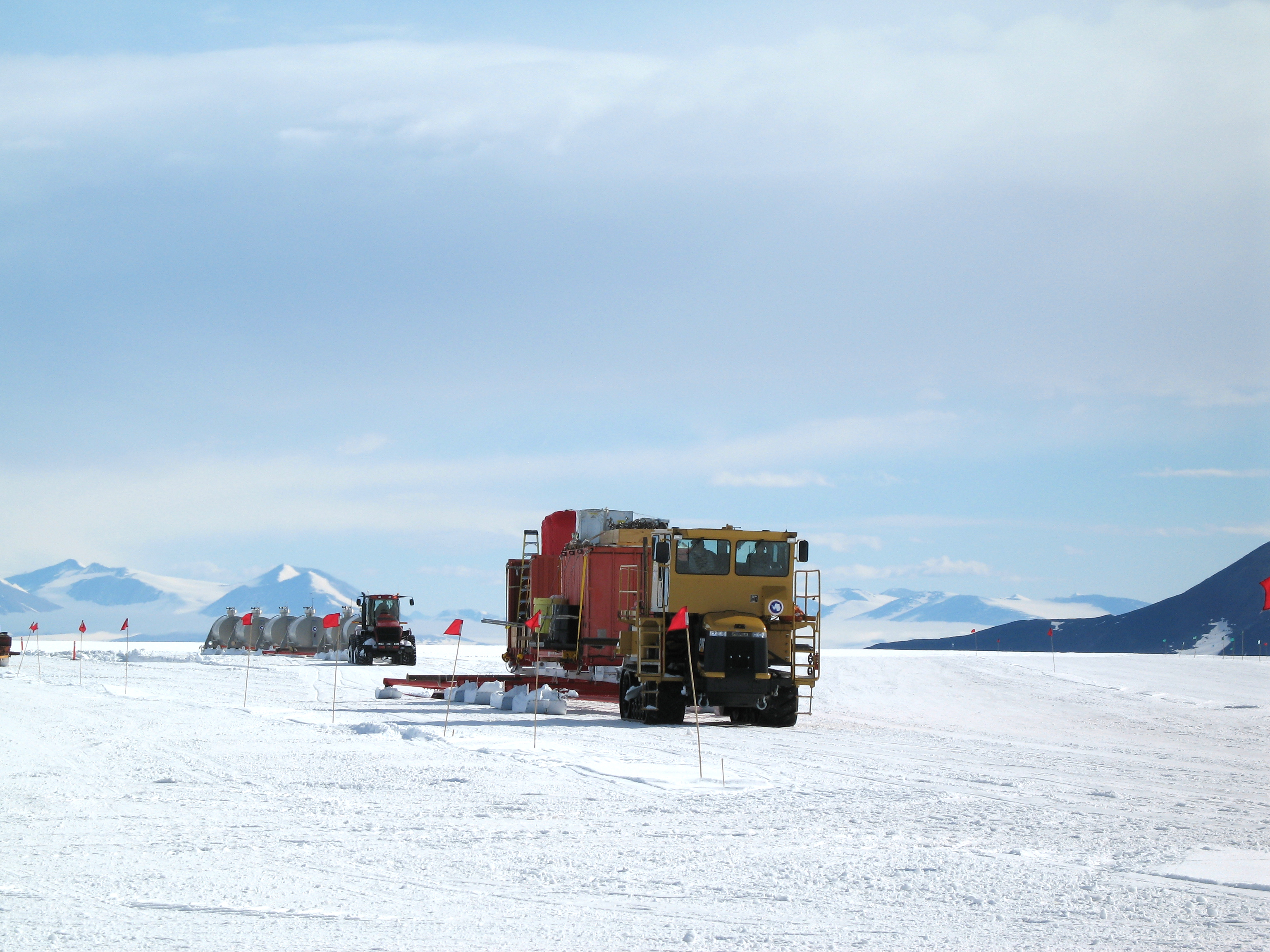 A tractor pulling large sleds across snow.