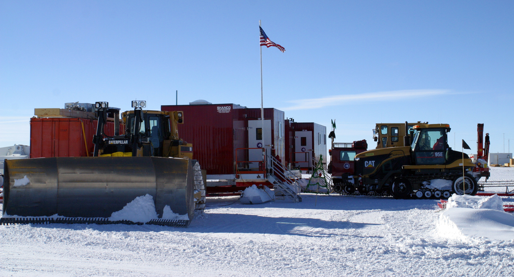 Several pieces of heavy equipment sit outside a small building.