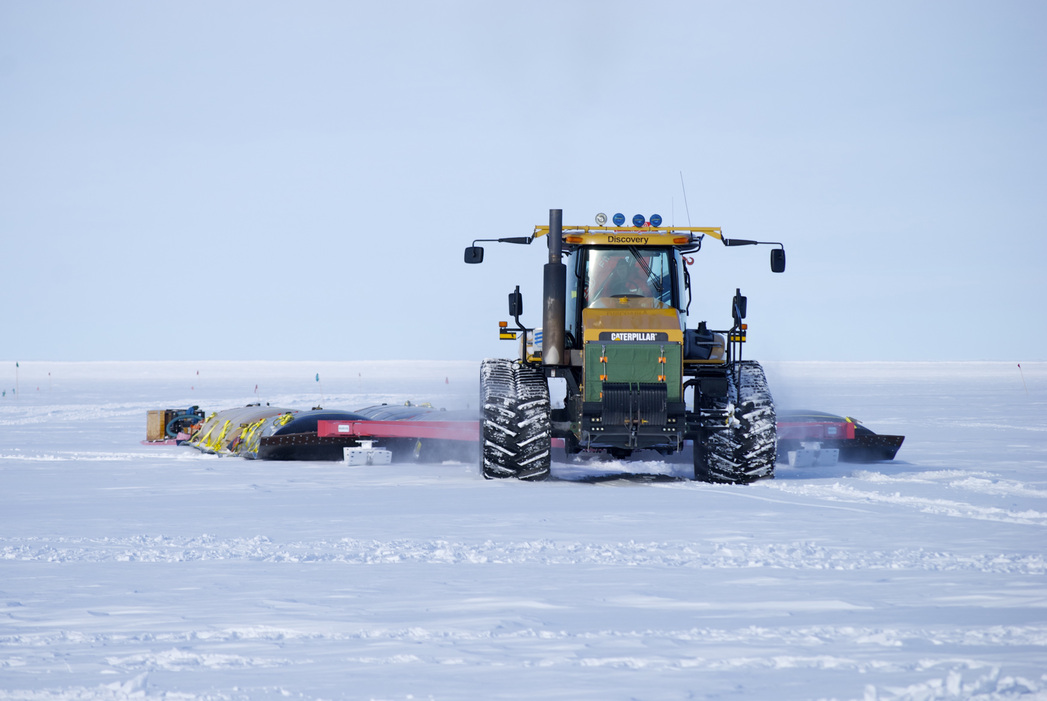 Tractor pulling a sled across snow.