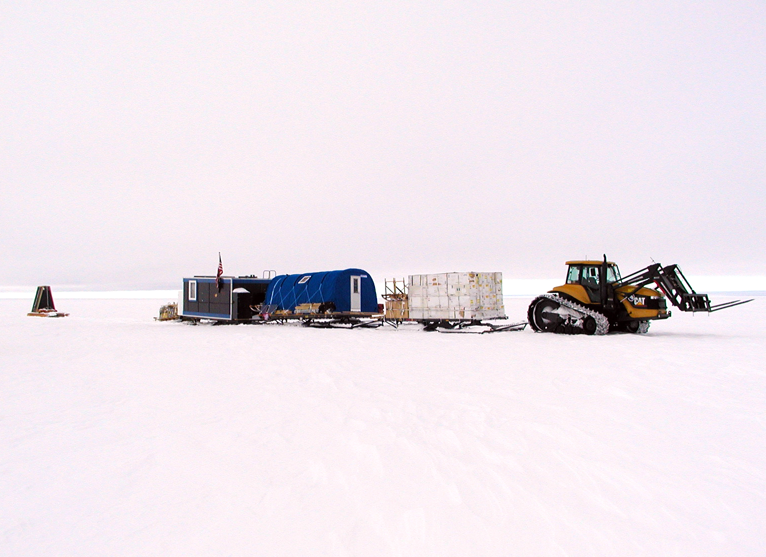 A tractor pulls sleds across the snow.