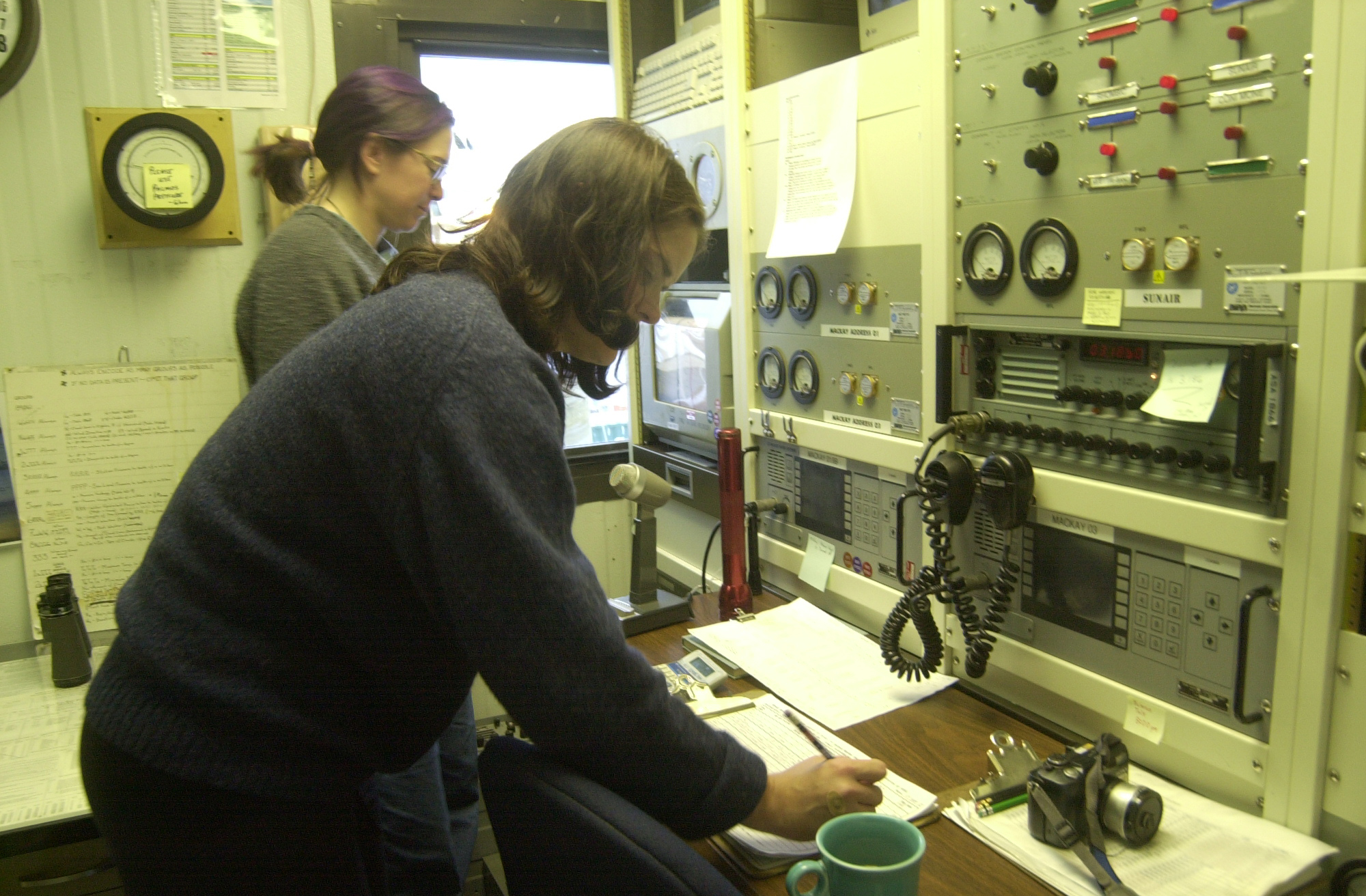 Two women in front of a control panel.