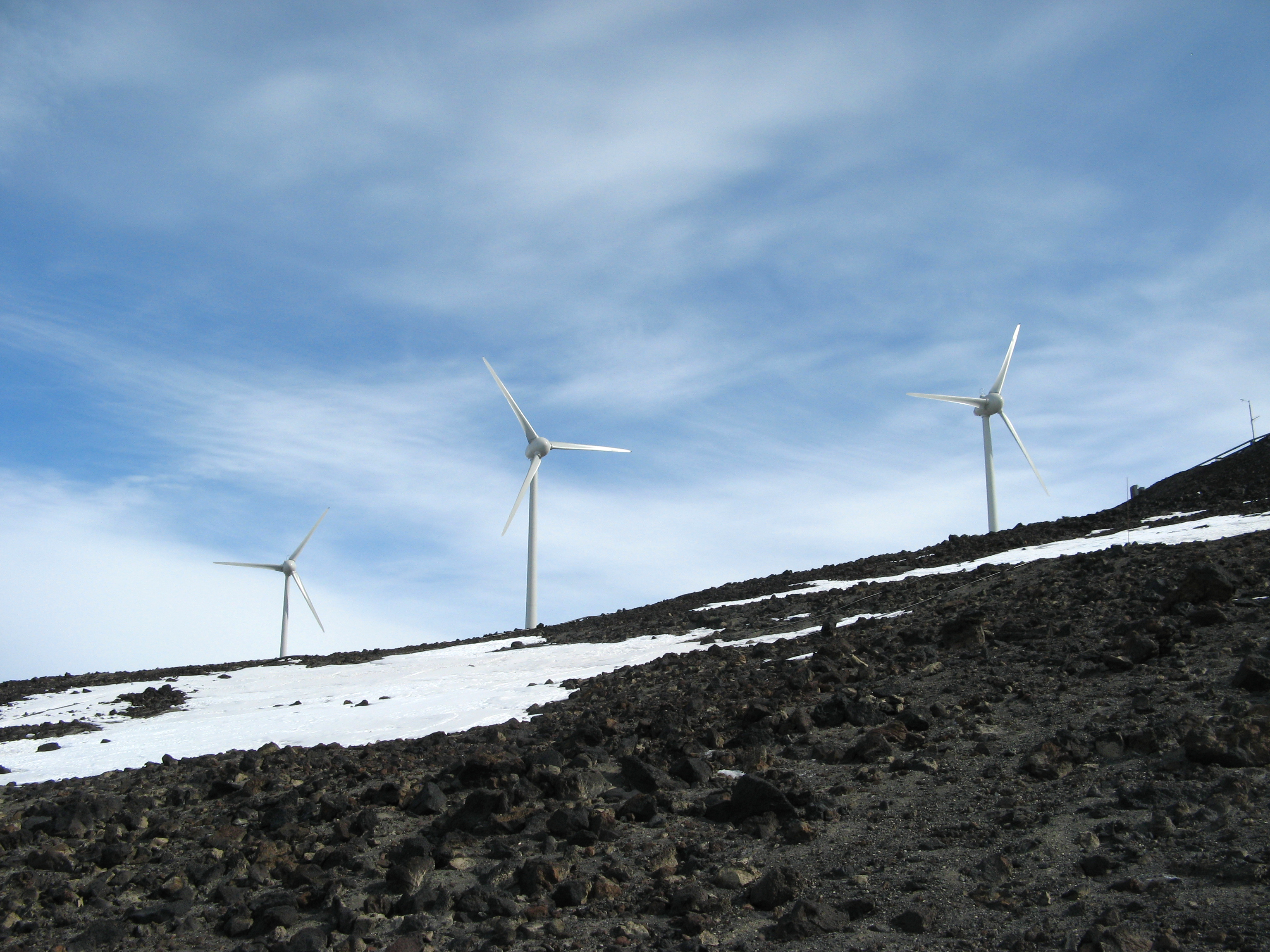 Wind turbines spin near icy place.