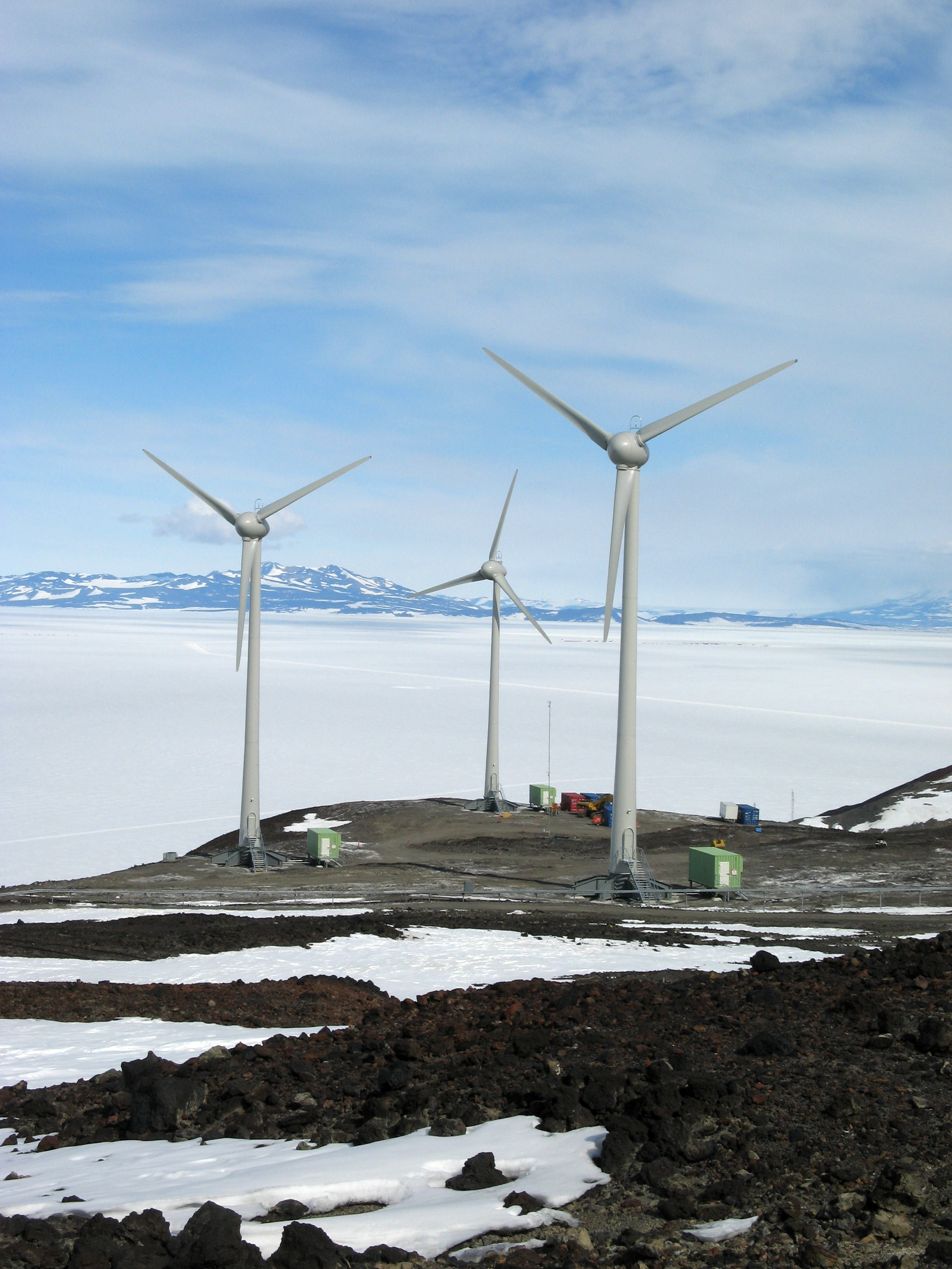 Wind turbines spin near icy place.