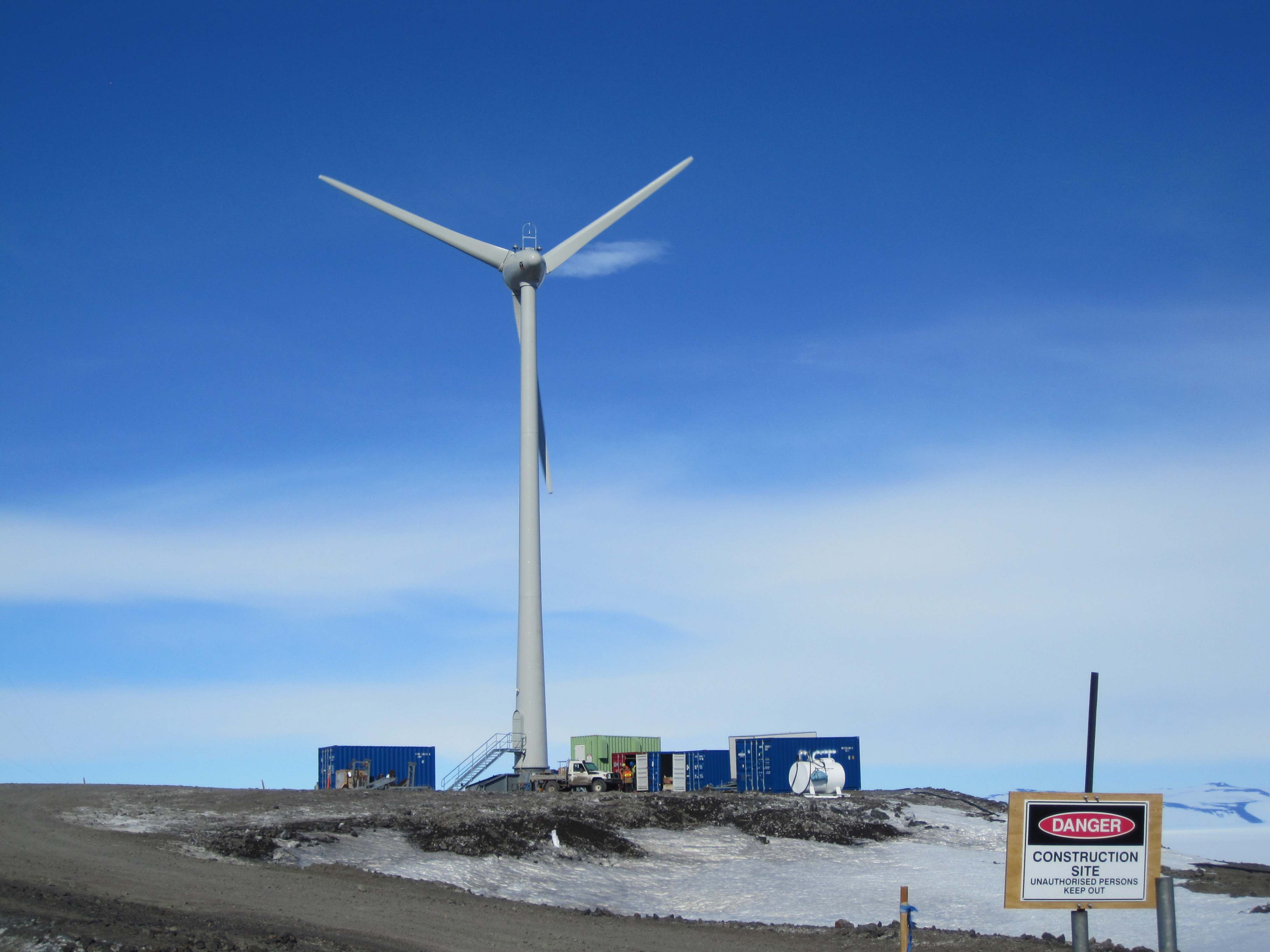 Wind turbine spins under blue sky.