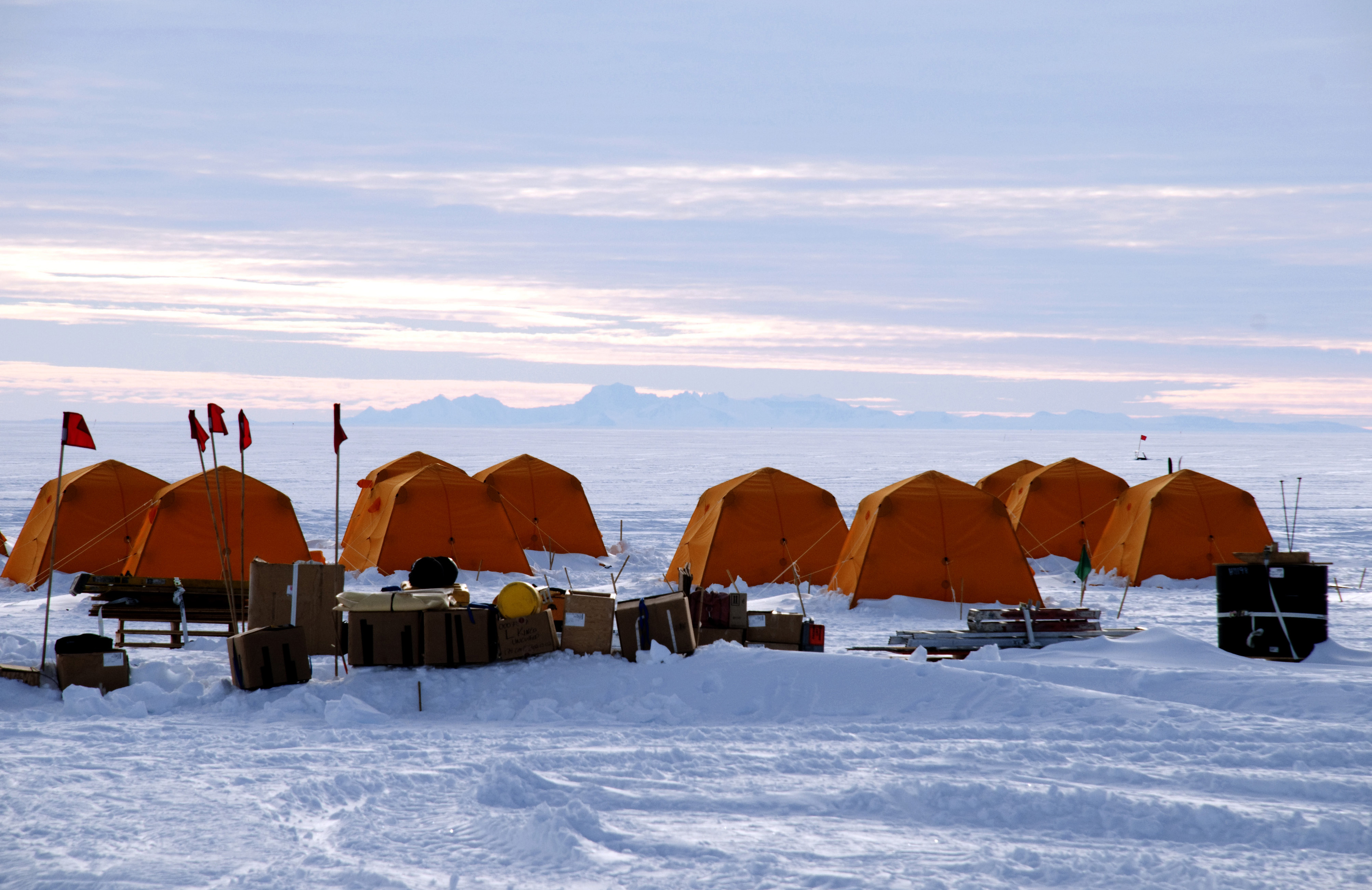 Group of tents set up on ice surface.