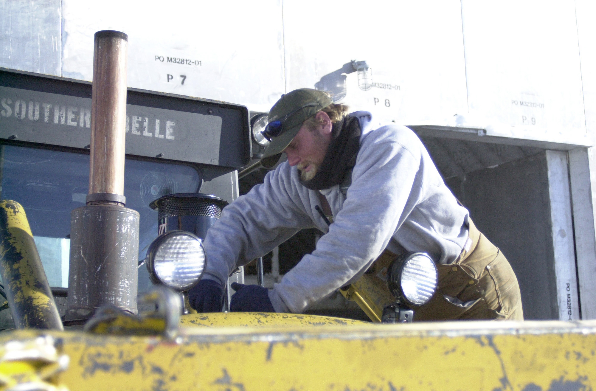 A man works on an old tractor.