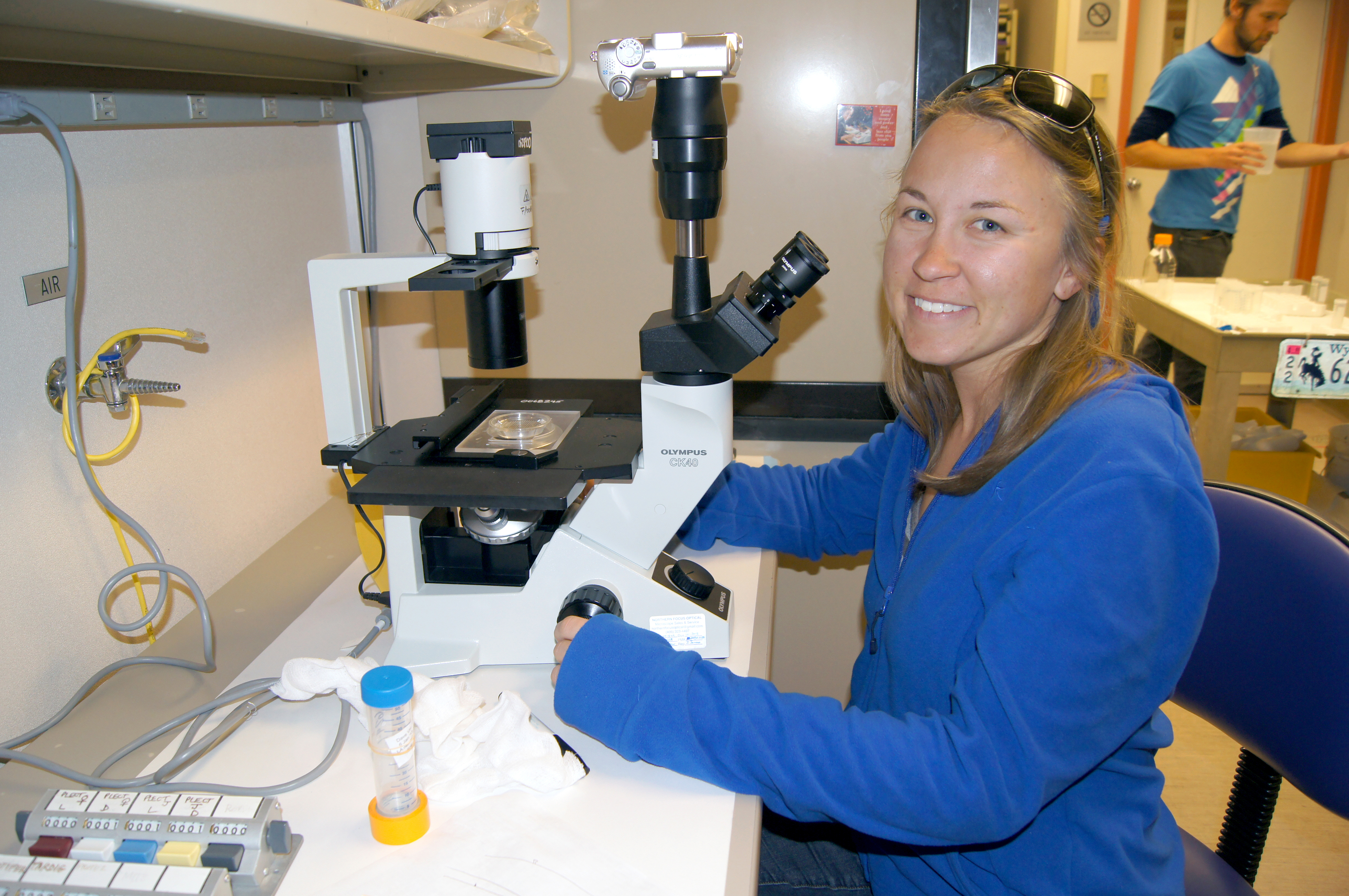 A woman at a microscope.