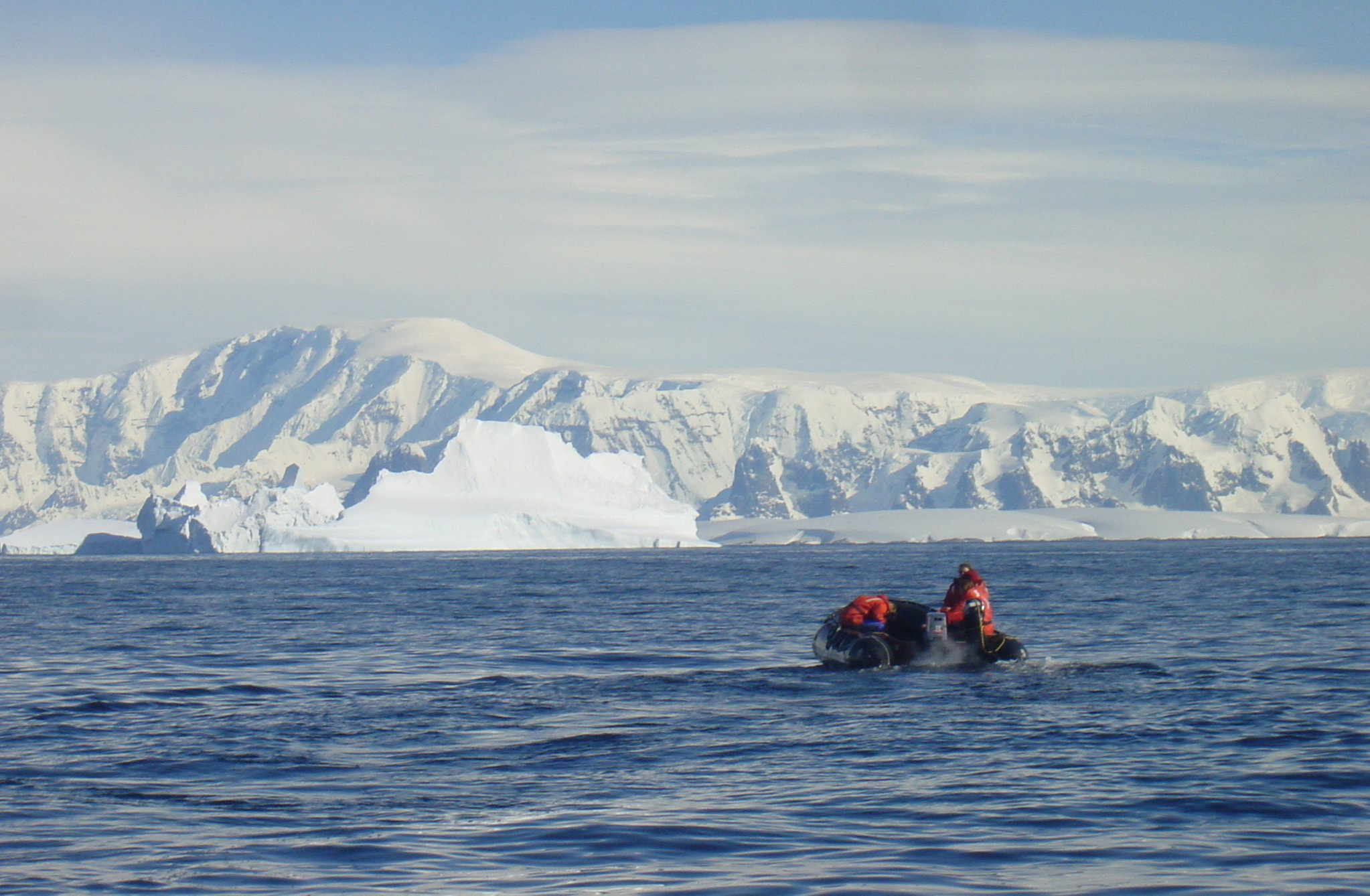 People in a zodiac inflatable raft are on open water.