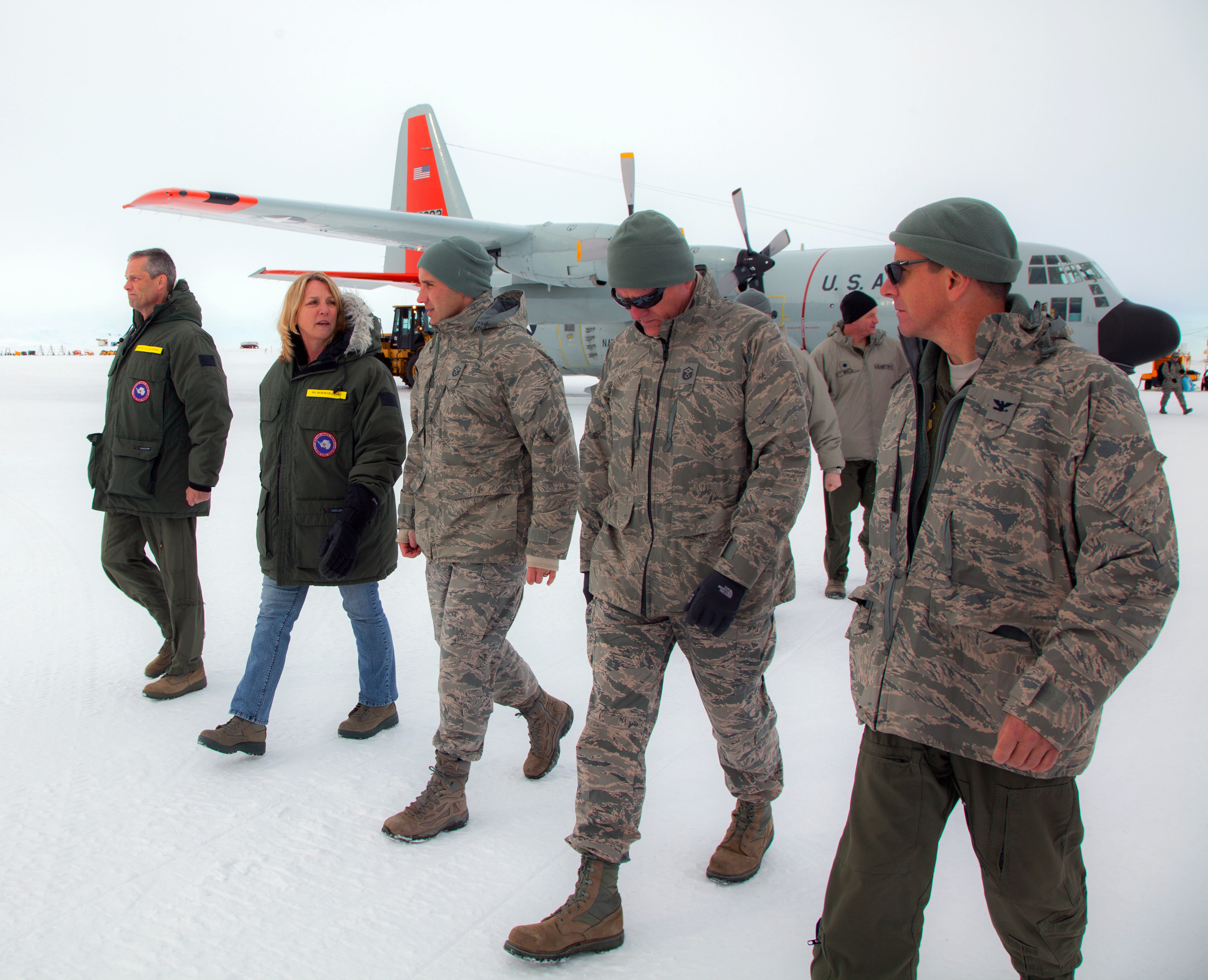 Five people walk away from an airplane.